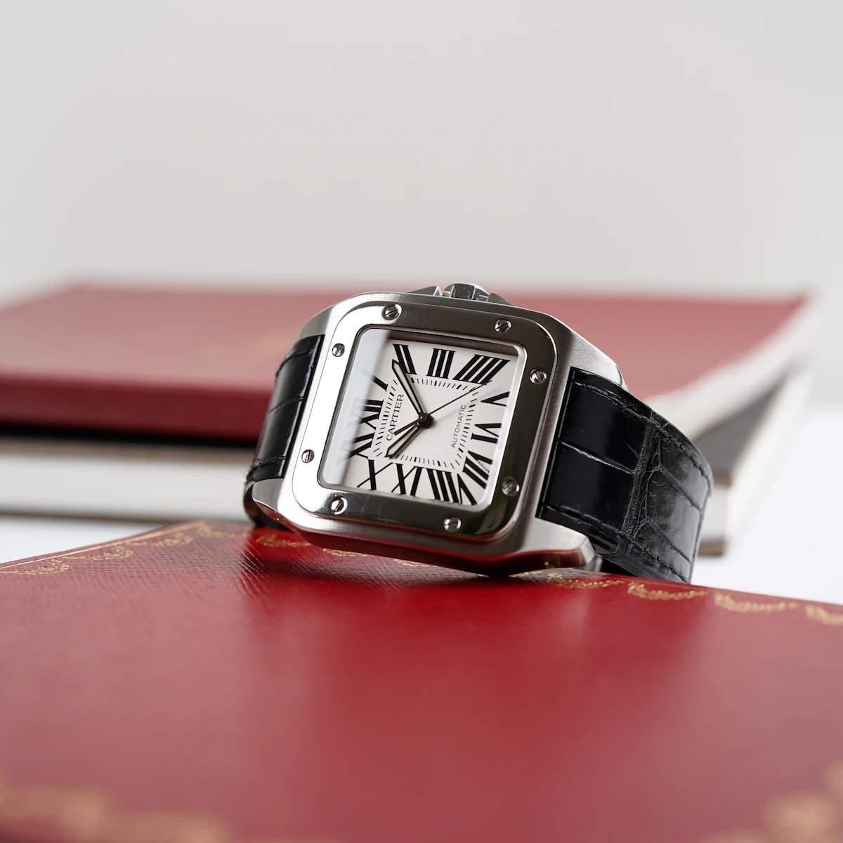 Cartier Santos XL am schwarzen Alligator-Lederband mit Dokumenten in den typischen Farben von Cartier.