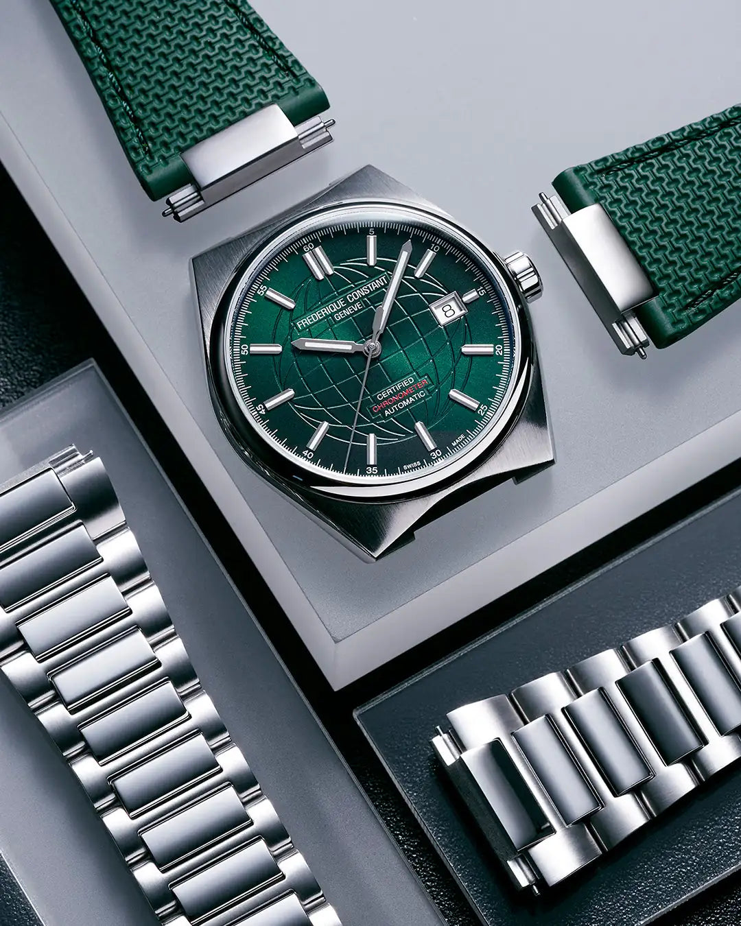 Produktfotografie der Highlife Automatic COSC Uhr von Frederique Constant mit dem grünen Zifferblatt zusammen mit den zwei mitgelieferten Armbändern in Edelstahl und grünem Kautschuk