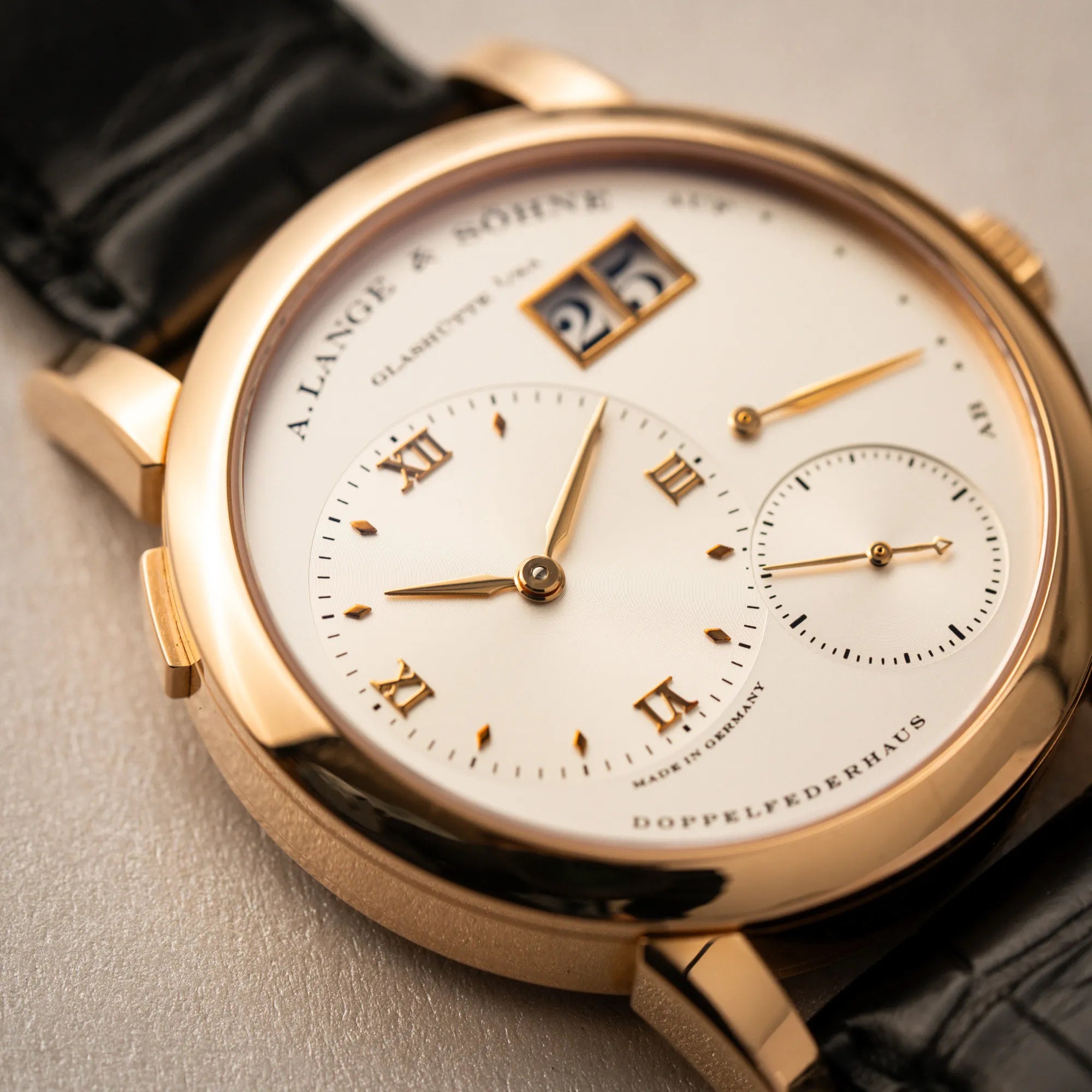 Sehr nahe Detailaufnahme der A. Lange & Söhne Lange 1 der Referenz 101.032 mit 38,5mm-Roségold-Gehäuse und dem für das Modell typische, asymmetrisch angeordnete Zifferblatt mit Großdatum