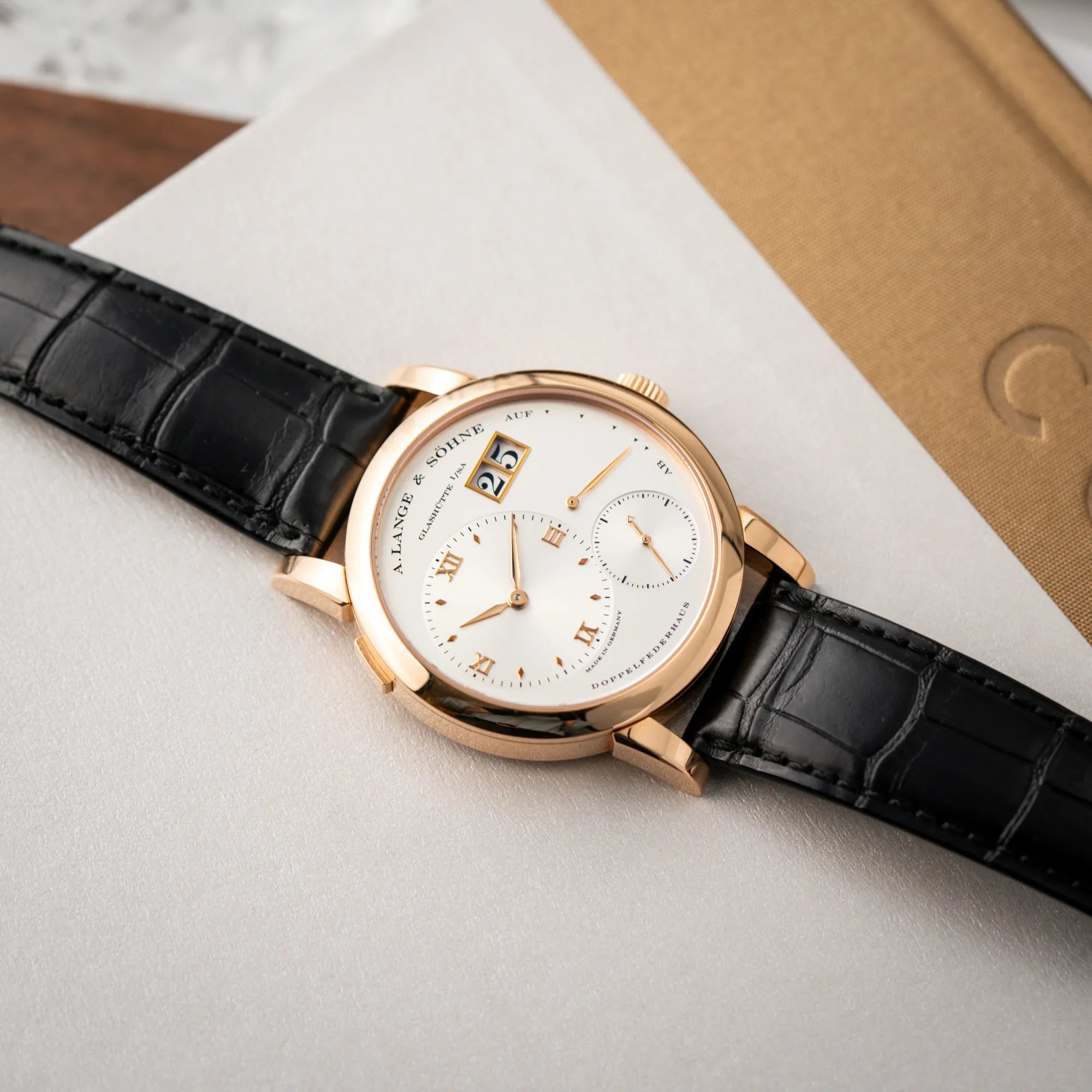 Produktfotografie der A. Lange & Söhne Lange 1 der Referenz 101.032 mit 38,5mm-Roségold-Gehäuse und dem für das Modell typische, asymmetrisch angeordnete Zifferblatt mit Großdatum in einem Silberton