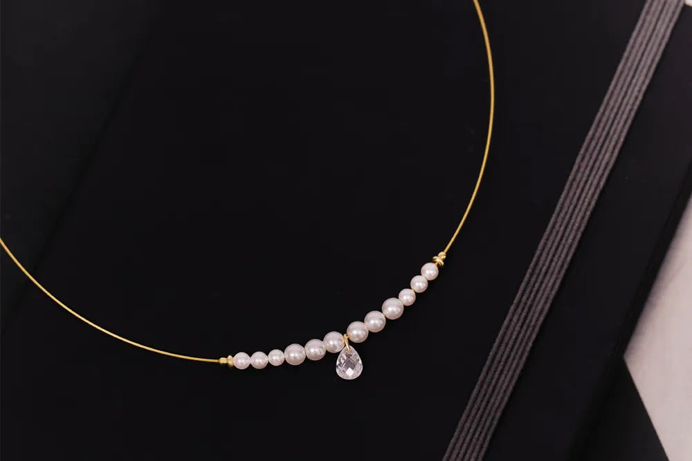 Goldfarbenes Collier von Alisia Schmuck mit Perlen und einem zentralen durchbohrten Zirkoia-Stein im Perlenschliff
