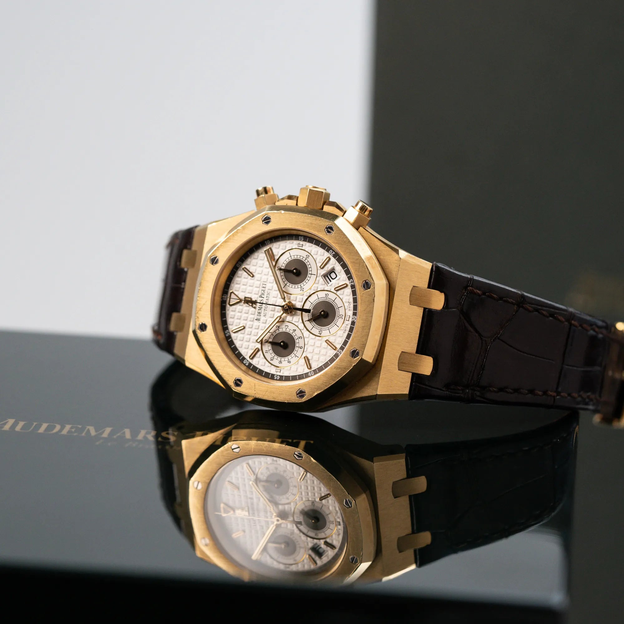 Produktfotografie des seitlich liegenden gelbgoldenen Royal Oak Chronographs von Audemars Piguet mit einem 39mm Gelbgold-Gehäuse und braunen Lederband