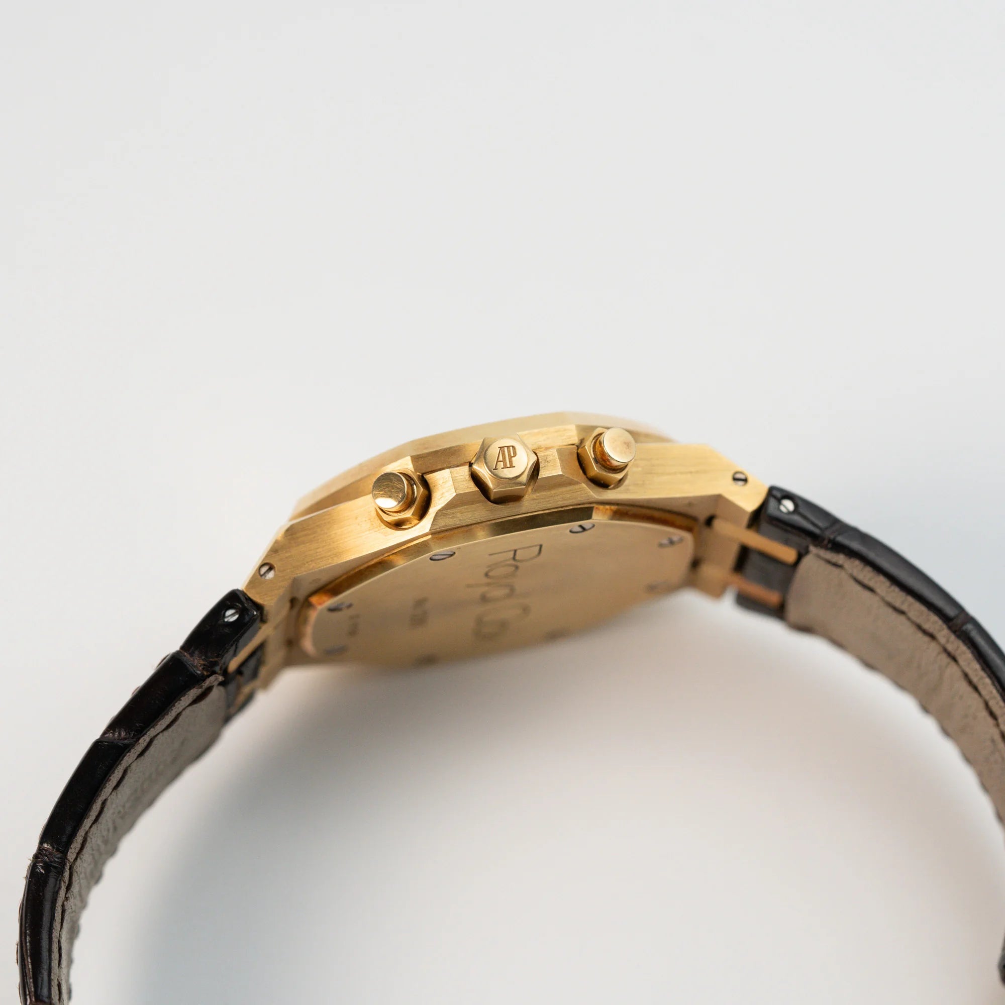 Seitliches Gehäuse mit Blick auf die Krone und Chrono-Pusher des gelbgoldenen Royal Oak Chronographen von Audemars Piguet mit 39mm Gehäusedurchmesser an einem dunkelbraunen Lederband