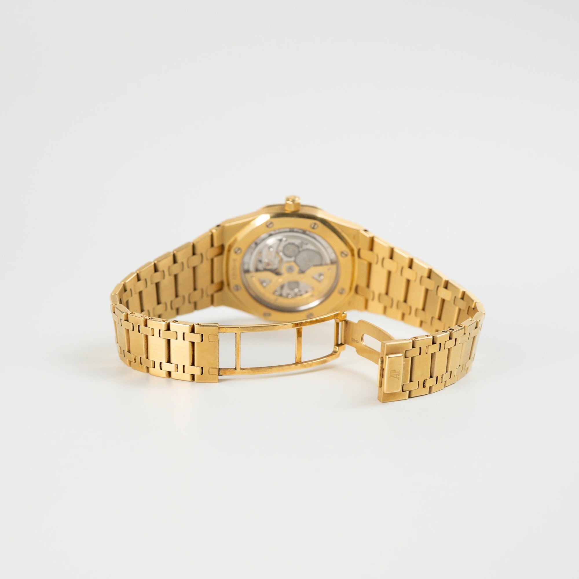 Blick auf den Gehäuseboden einer liegenden Audemars Piguet Royal Oak Jumbo 14802BA Jubilee in Gelbgold mit gläsernem Caseback und geöffneter Armband-Schließe