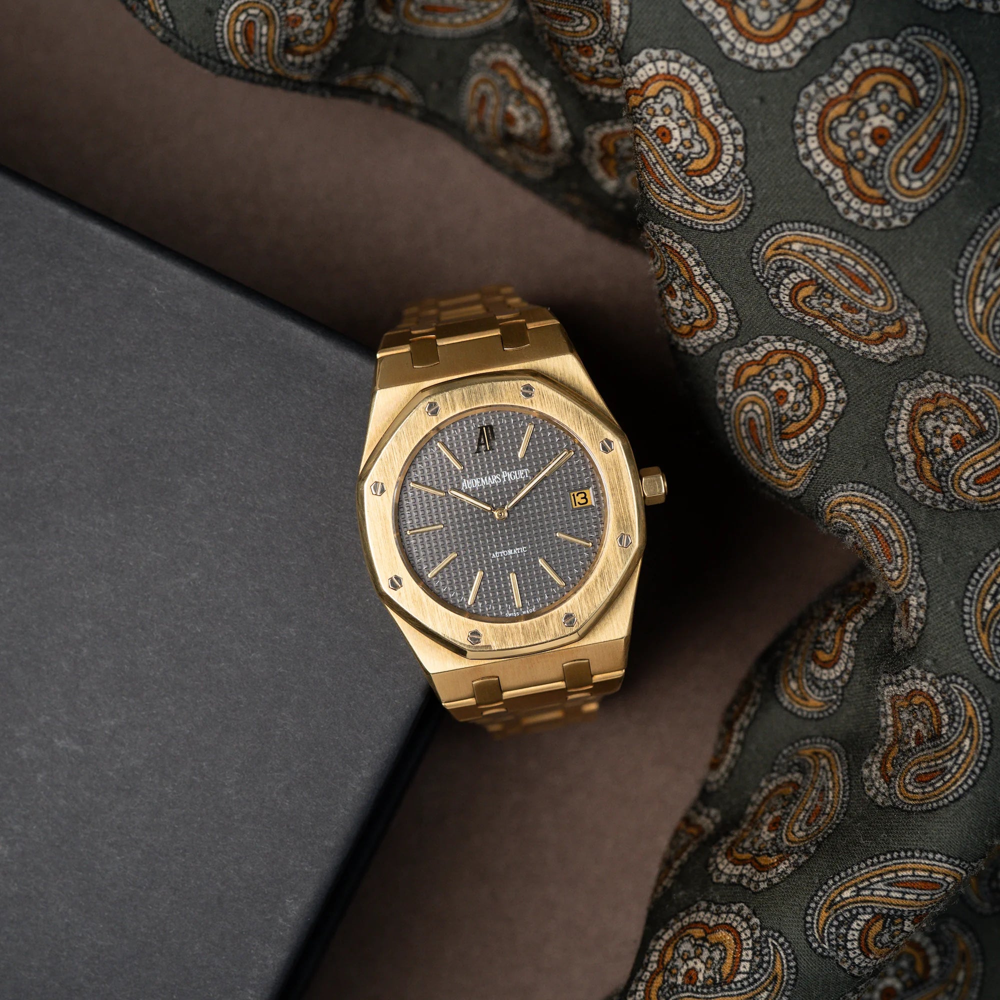Audemars Piguet Royal Oak Jumbo 14802BA Jubilee in Gelbgold steht neben einem grünen Tuch mit Muster