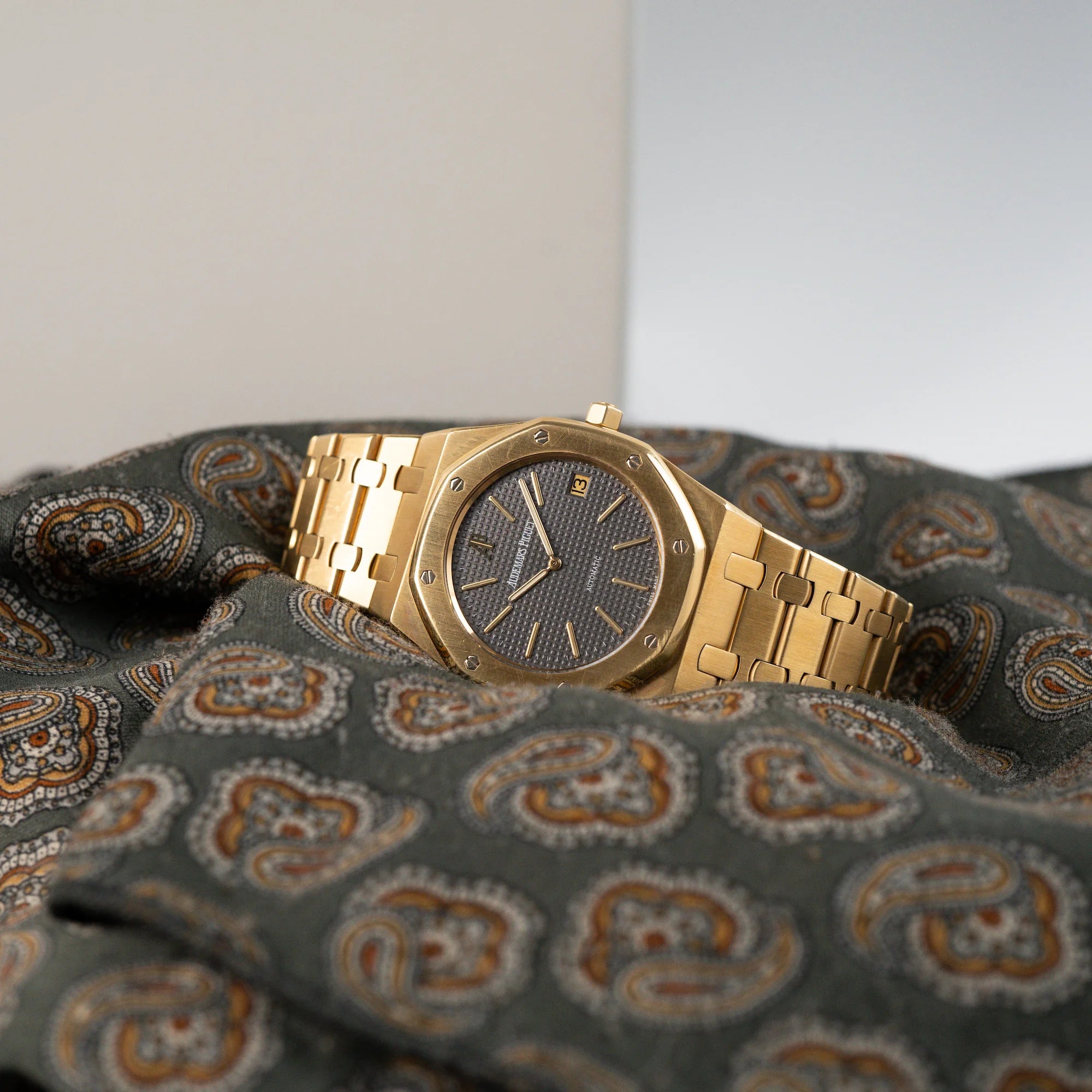 Audemars Piguet Royal Oak Jumbo 14802BA Jubilee in Gelbgold liegt auf einem grünen Tuch mit Muster