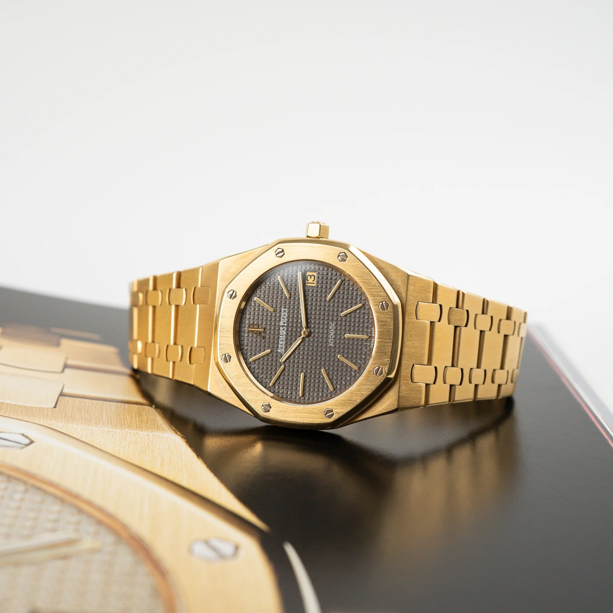 Audemars Piguet Royal Oak Jumbo 14802BA Jubilee in Gelbgold liegt auf einem Buch, das die Uhr selbst auch abbildet