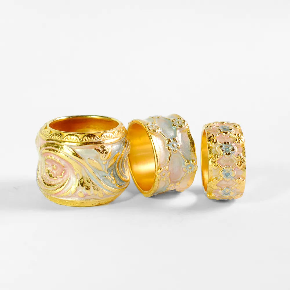 Goldfarbene Ringe für Damen von Barbara Haas mit Pflanzendesign, welche mit rosa und hellblauem Lack veredelt wurden