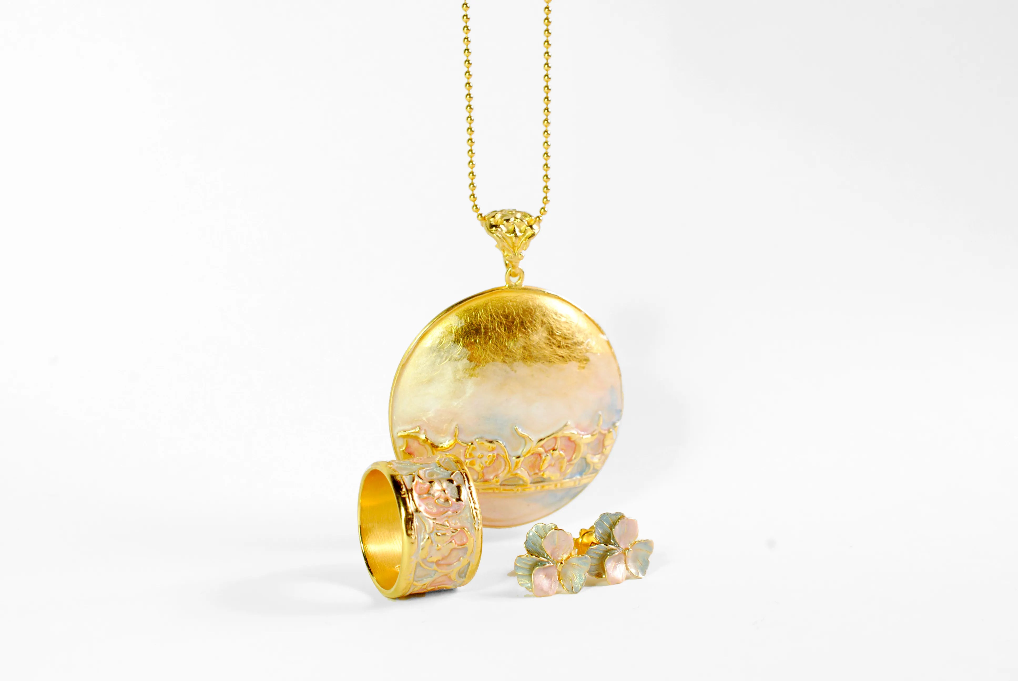 Produktfotografie eines goldfarbenen Ring, Halsketten mit Amulet-Anhönger und einem Paar Ohrstecker im Blumendesign aus der Kollektion von Barbara Haas Design