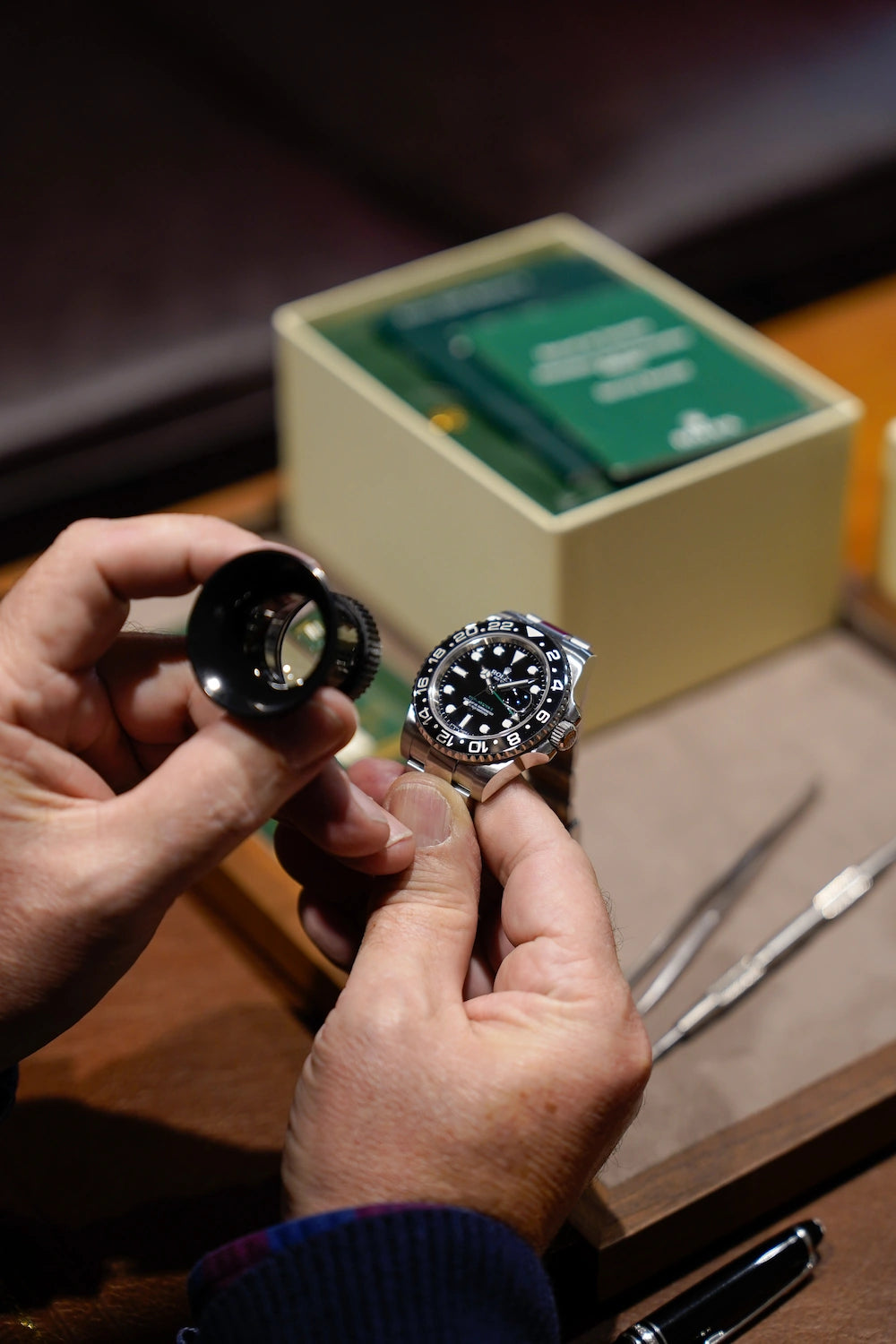 Bewerten des Zustands einer Rolex GMT Master 12670BLNR mit einer Lupe