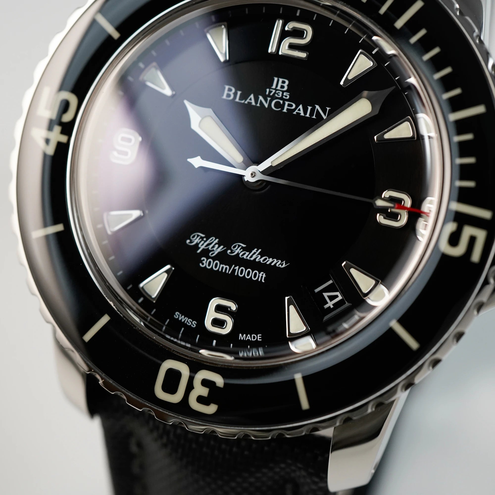 Detailaufnahme des Zifferblatts der Blancpain Fifty Fathoms in Schwarz am Nylon-Band
