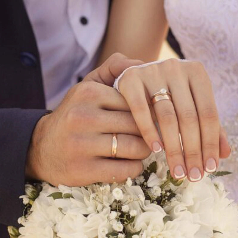 Hand des Bräutigams mit Ehering hält die Hand seiner Frau mit Ehering und Verlobungsring an Tag der Hochzeit