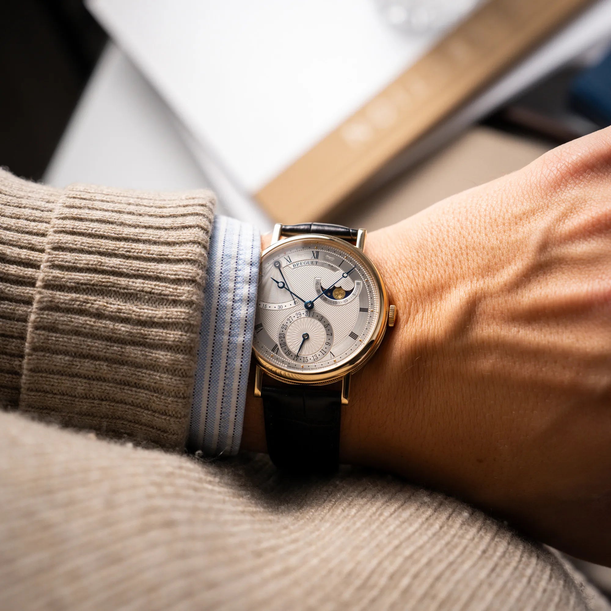 Mann trägt die Breguet Classique 7137BA mit einem Gelbgoldgehäuse in klassischer Form mit einem silbernen Zifferblatt mit jeweils einem anderen handgefertigten Guilloche-Muster für jede Komplikation an seinem Handgelenk