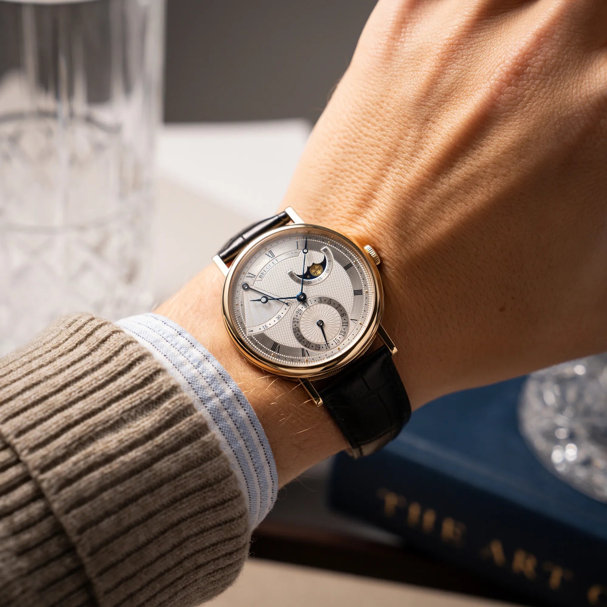 Mann trägt die Breguet Classique 7137BA mit einem Gelbgoldgehäuse in klassischer Form mit einem silbernen Zifferblatt mit jeweils einem anderen handgefertigten Guilloche-Muster für jede Komplikation für einen Wristshot an seinem Handgelenk