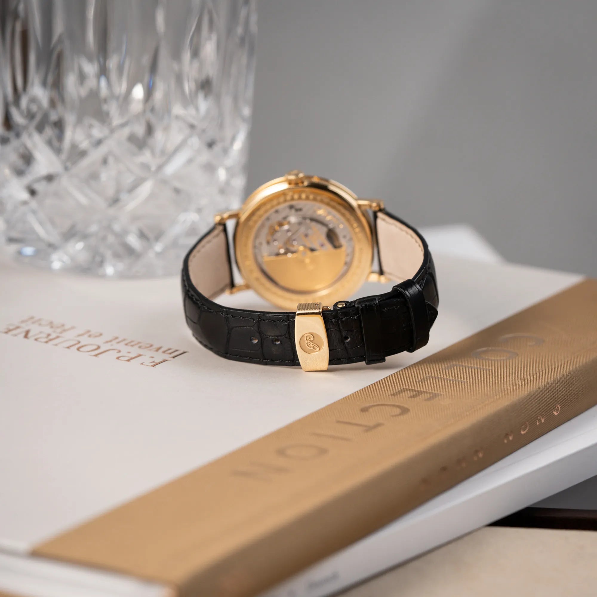 Produktfotografie der Breguet Classique 7137BA mit einem Gelbgoldgehäuse in klassischer Form mit einem silbernen Zifferblatt mit jeweils einem anderen handgefertigten Guilloche-Muster für jede Komplikation mit Fokus auf dem Lederband und der Gelbgold-Schliesse