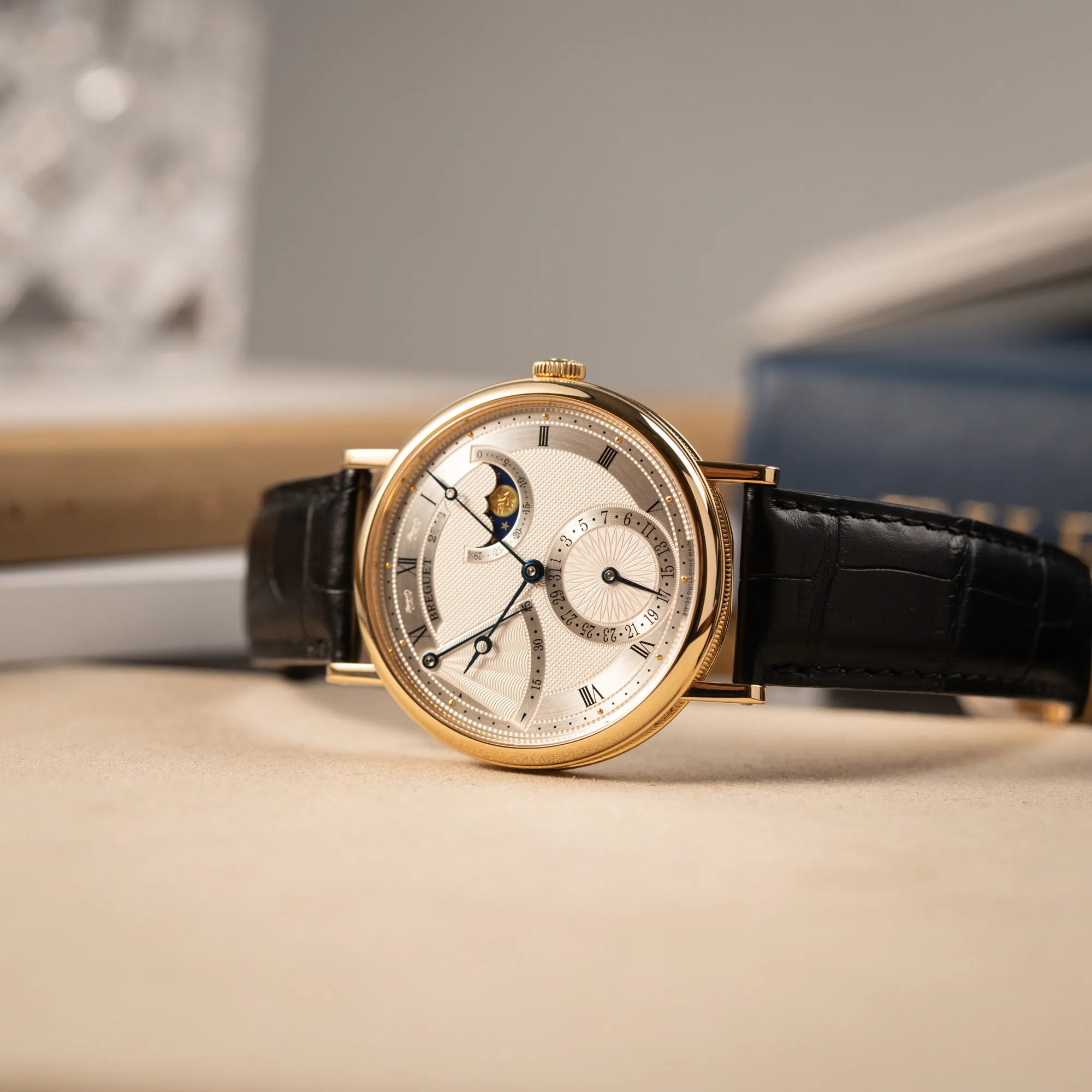 Produktfotografie der Breguet Classique 7137BA mit einem Gelbgoldgehäuse in klassischer Form mit einem silbernen Zifferblatt mit jeweils einem anderen handgefertigten Guilloche-Muster für jede Komplikation