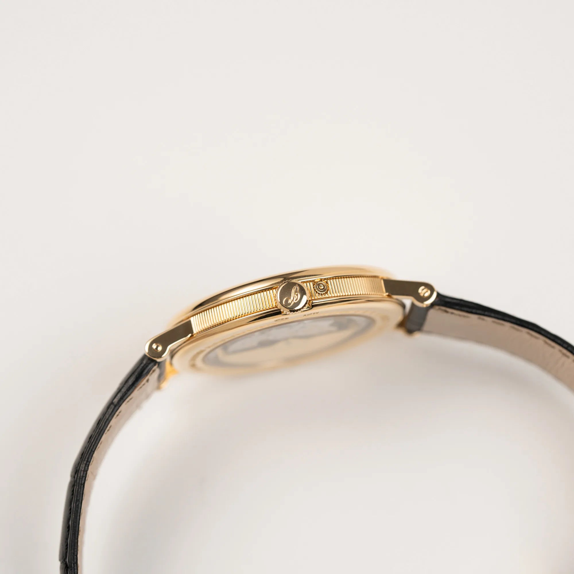 Seitliche Gehäuseflanke mit Kannellierung von der Breguet Classique 7137BA mit einem Gelbgoldgehäuse in klassischer Form mit einem silbernen Zifferblatt mit jeweils einem anderen handgefertigten Guilloche-Muster für jede Komplikation zeigt die Aufzugskrone
