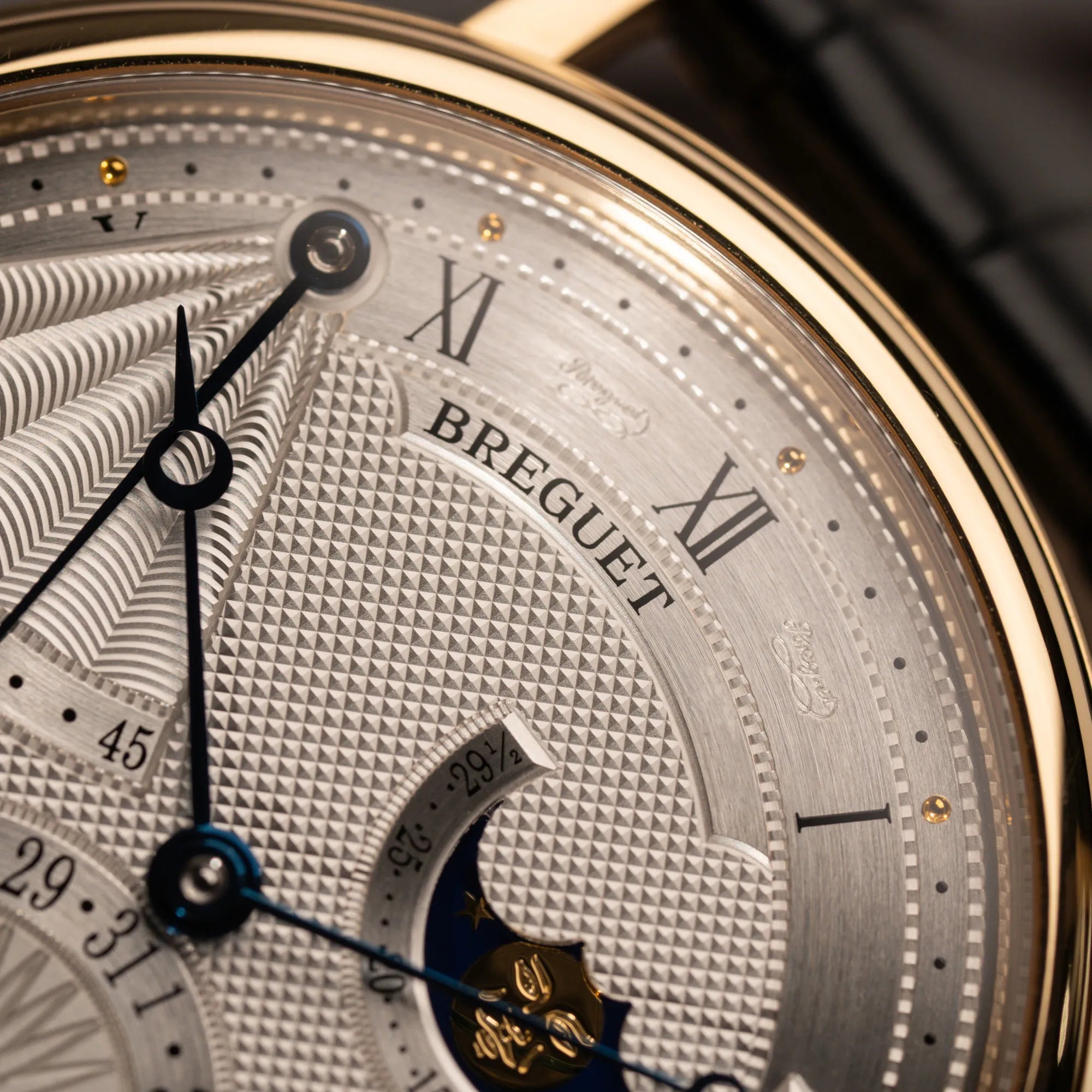 Detailaufnahme der gelbgoldenen Lünette bei der Breguet Classique Mondphase 7137 in Gelbgold mit silbernen, verschieden guillochiertem Zifferblatt