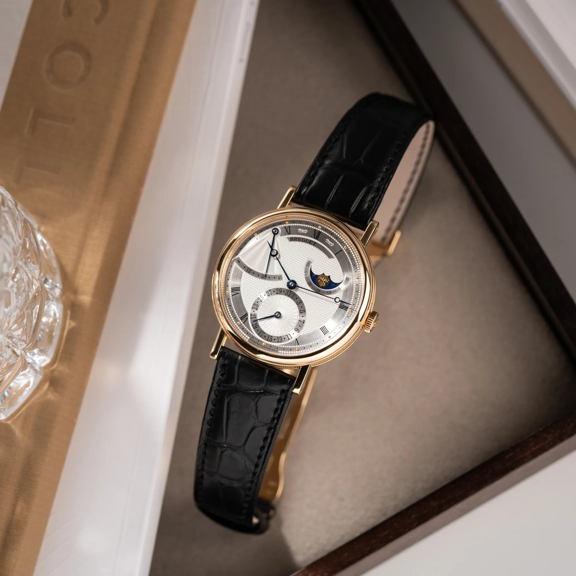 Produktfotografie von der Breguet Classique Mondphase 7137 in Gelbgold mit silbernen, verschieden guillochiertem Zifferblatt auf Juwelierstablet