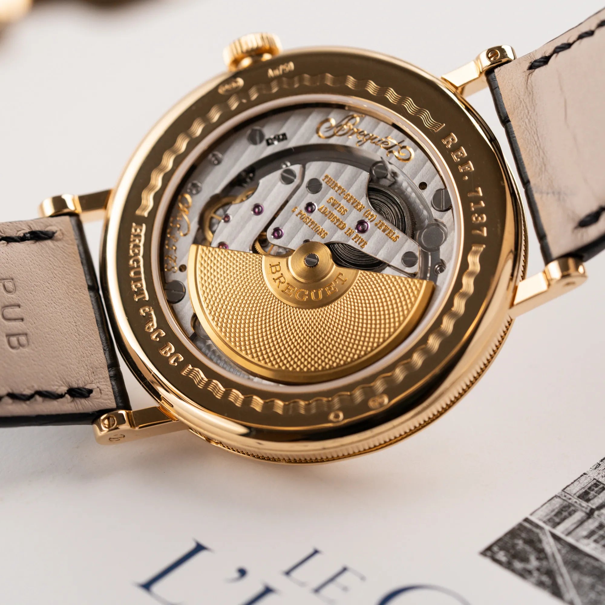 Detailaufnahme des Sichtbodens mit Blick auf den micro-Rotor der Breguet Classique Mondphase 7137 in Gelbgold mit silbernen, verschieden guillochiertem Zifferblatt