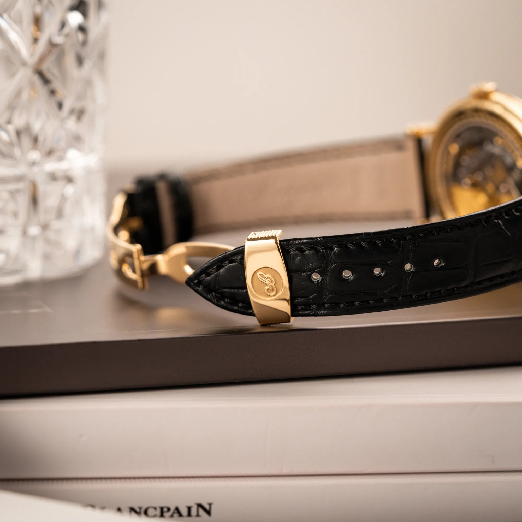 Detailaufnahme der originalen Breguet-Faltschliesse aus 750er Gelbgold an dem schwarzen Lederband der Breguet Classique Mondphase 7137 in Gelbgold mit silbernen, verschieden guillochiertem Zifferblatt