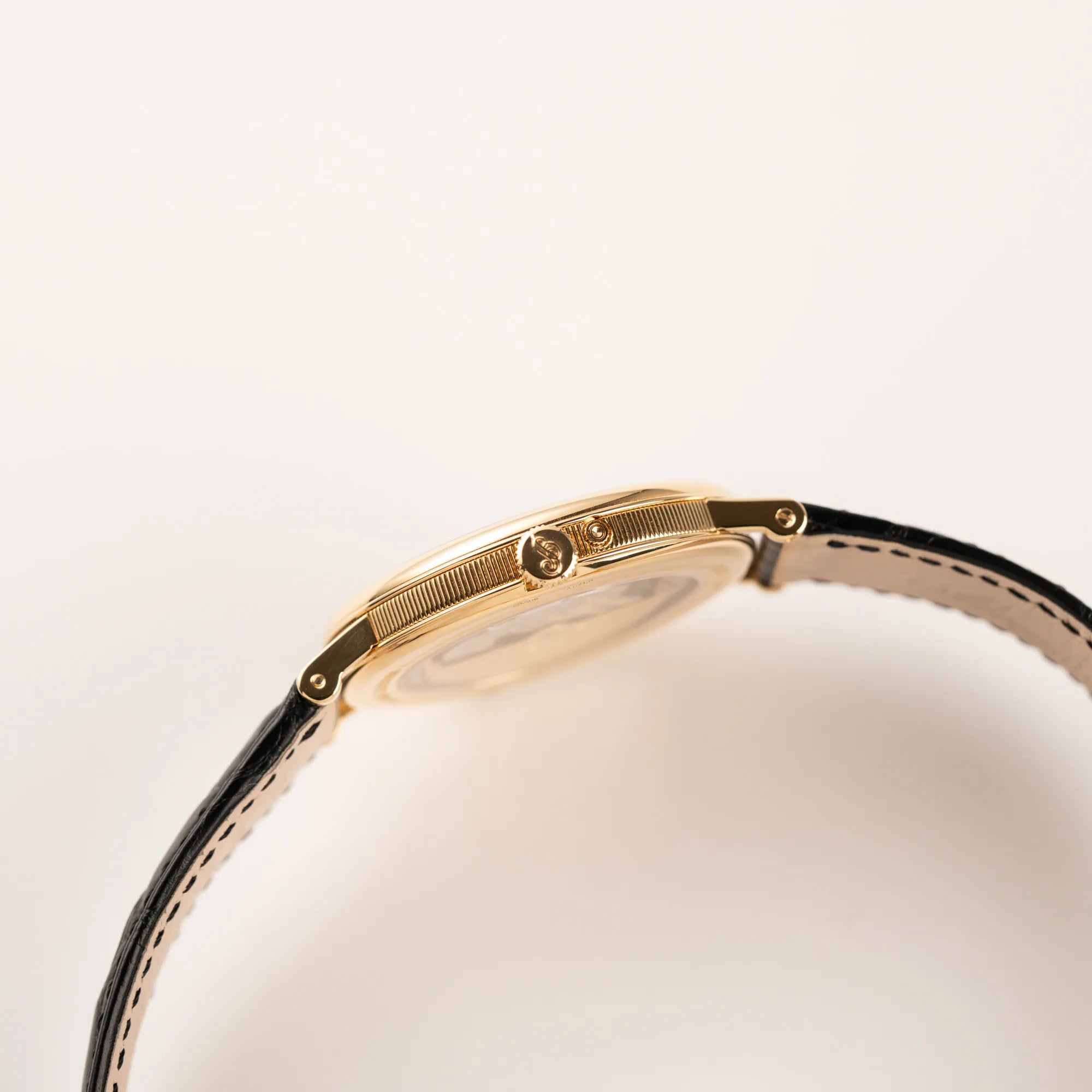 Seitliches Gehäuse der Breguet Classique Mondphase 7137 in Gelbgold mit silbernen, verschieden guillochiertem Zifferblatt mit Blick auf die Aufzugskrone