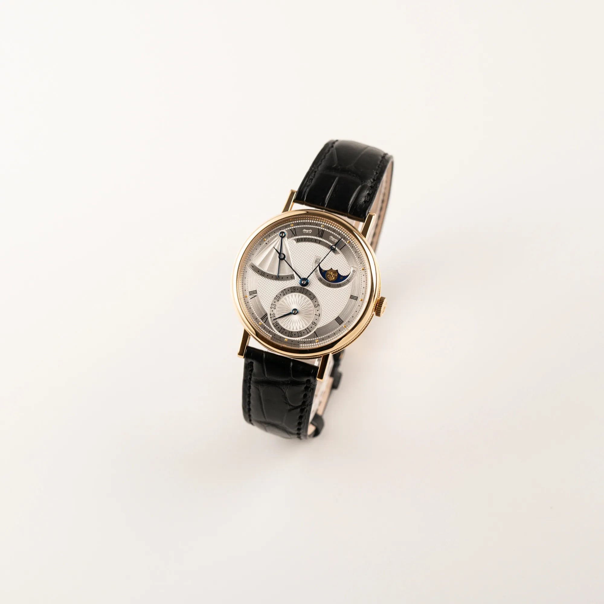 Leicht schräge Ansicht der Breguet Classique Mondphase 7137 in Gelbgold mit silbernen, verschieden guillochiertem Zifferblatt