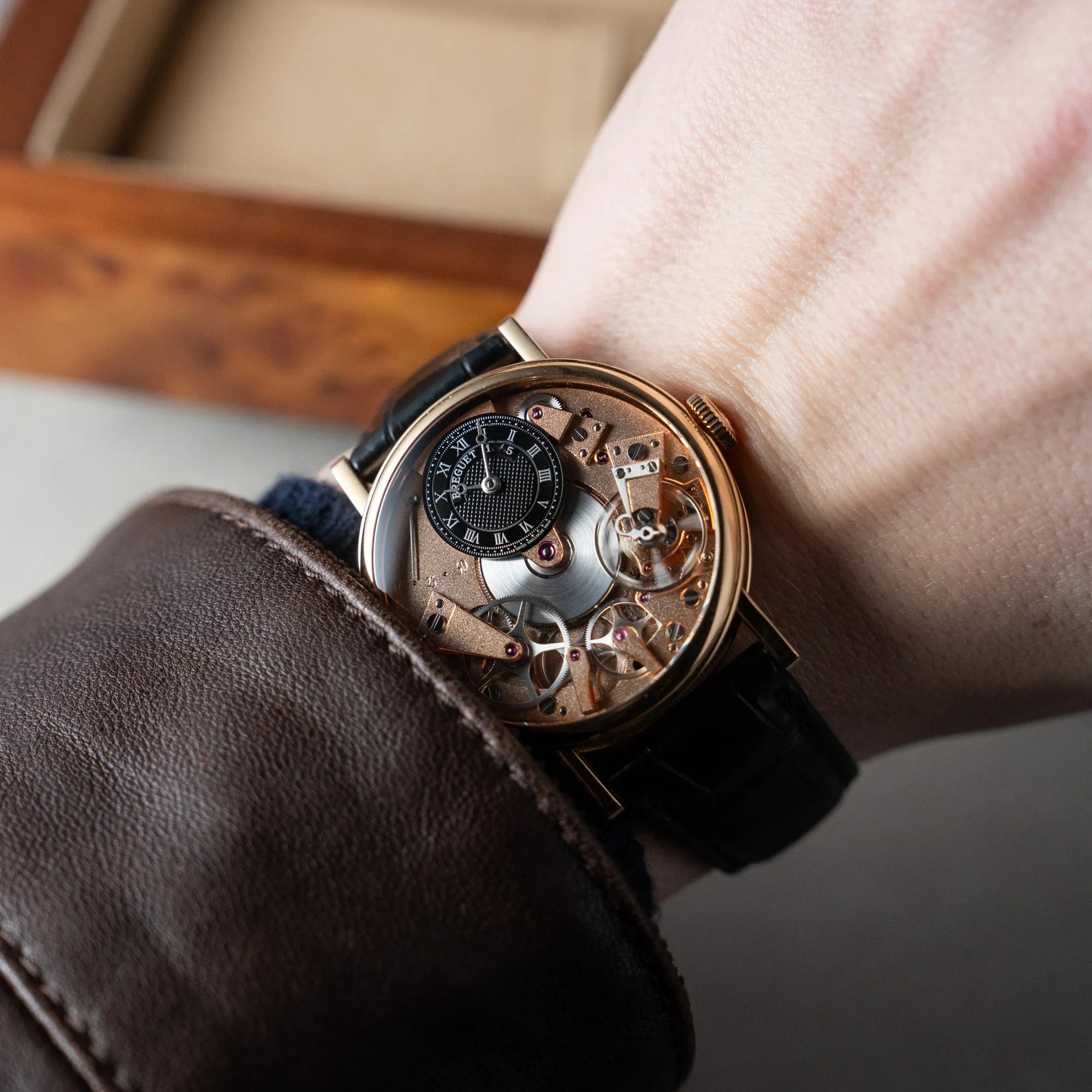 Mann trägt die klassische Breguet Tradition Armbanduhr mit Rosegold-Gehäuse und schwarzem Zifferblatt an seinem Handgelenk
