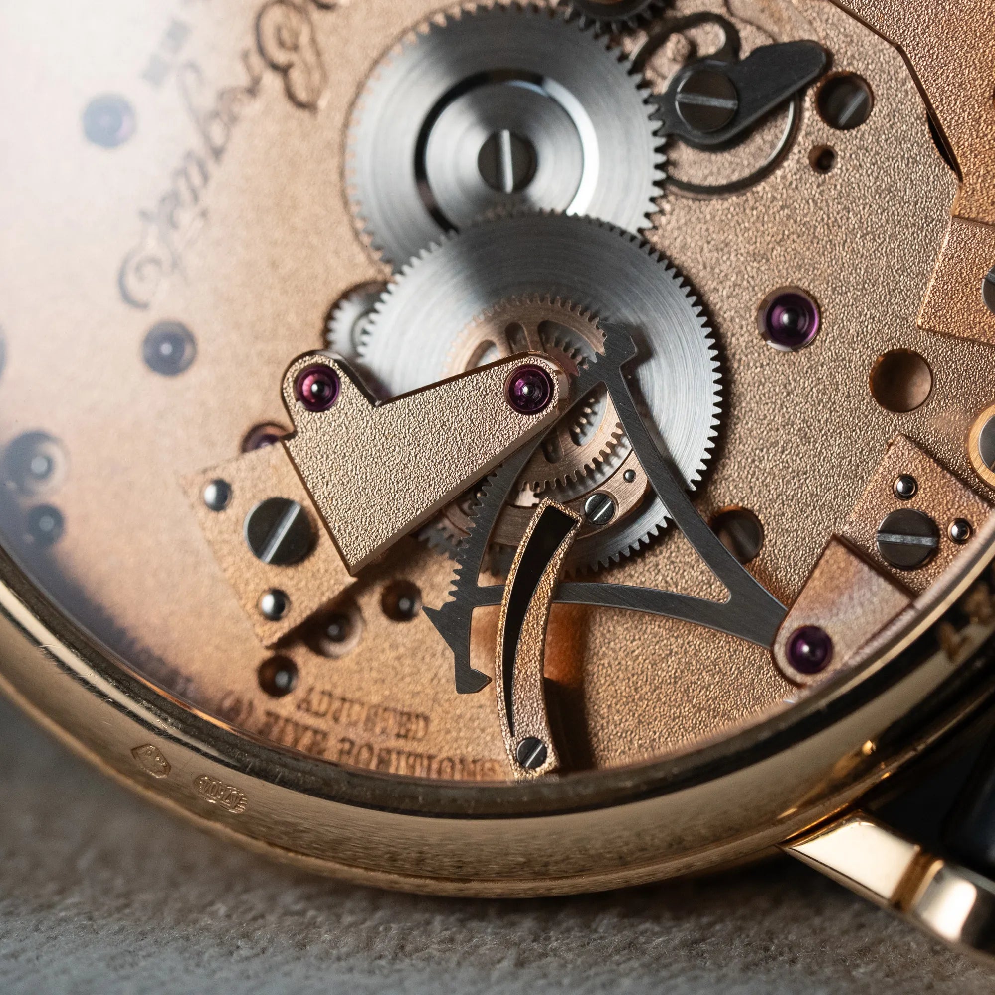 Detailaufnahme des Uhrwerks durch den gläsernen Gehäuseboden der klassischen Breguet Tradition Armbanduhr mit Rosegold-Gehäuse und schwarzem Zifferblatt