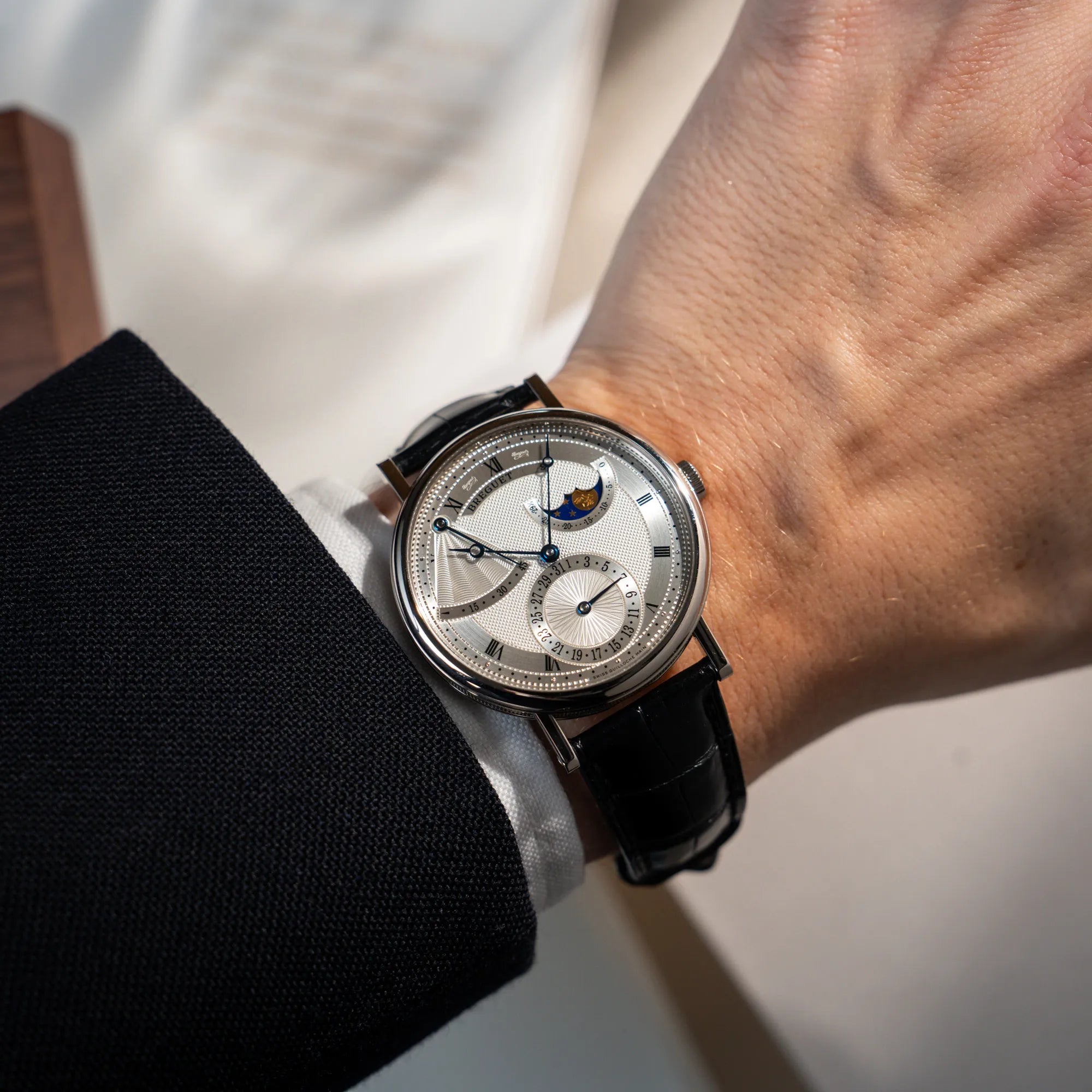 Mann trägt die Breguet Classique Moonphase der Referenz 7137 in Weissgold mit 3-fach guillochiertem Zifferblatt und Mondphase-Anzeige am Handgelenk