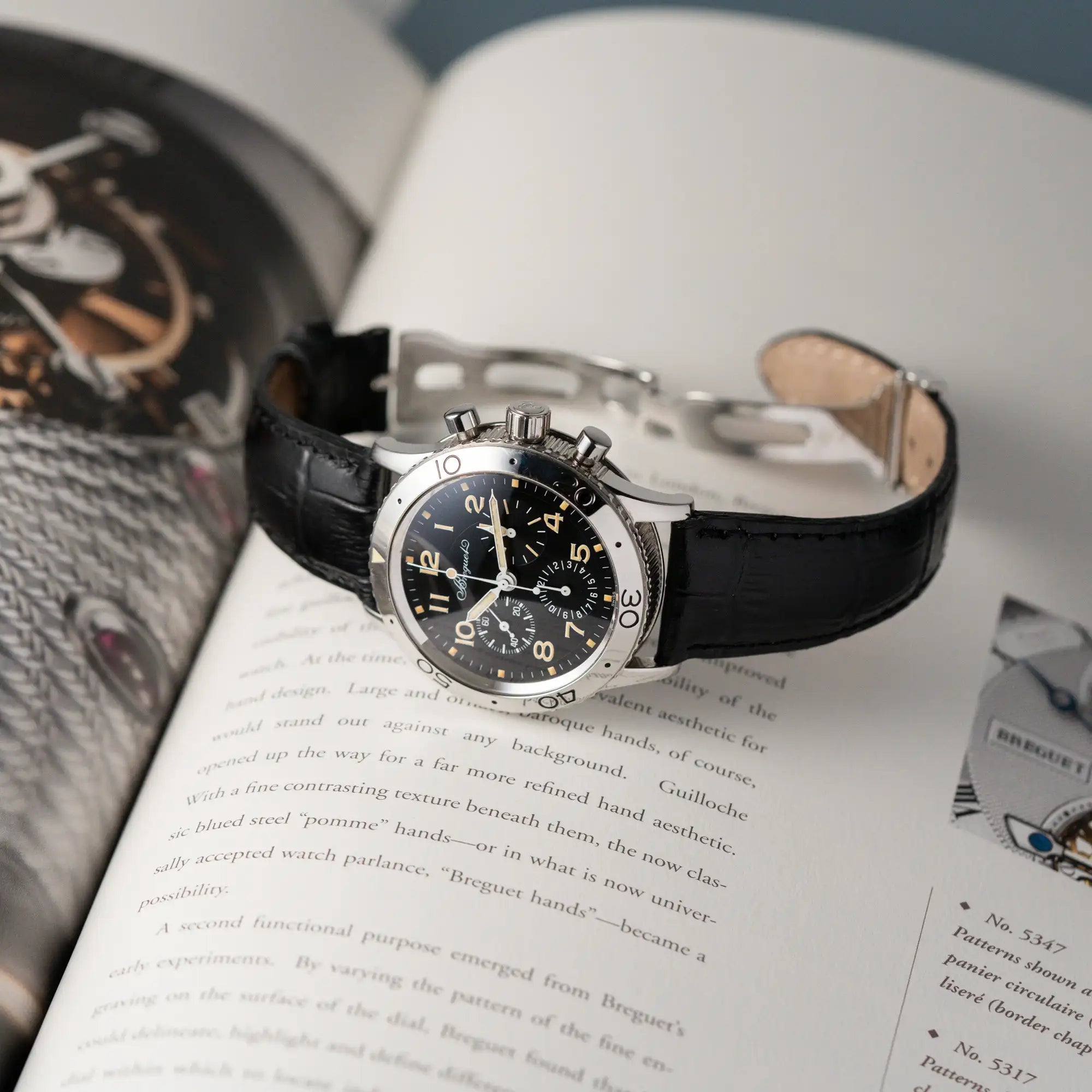 Produktfotografie der liegenden Breguet Type XX Aéronavale mit der Referenz 3800ST und vergilbten Tritium-Zifferblatt am schwarzen Lederband