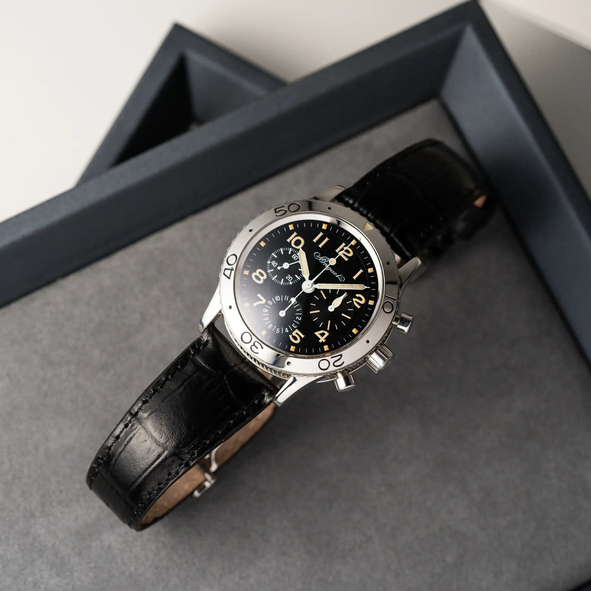 Produktfotografie der Breguet Type XX Aéronavale mit der Referenz 3800ST und vergilbten Tritium-Zifferblatt am schwarzen Lederband aus der Vogelperspektive