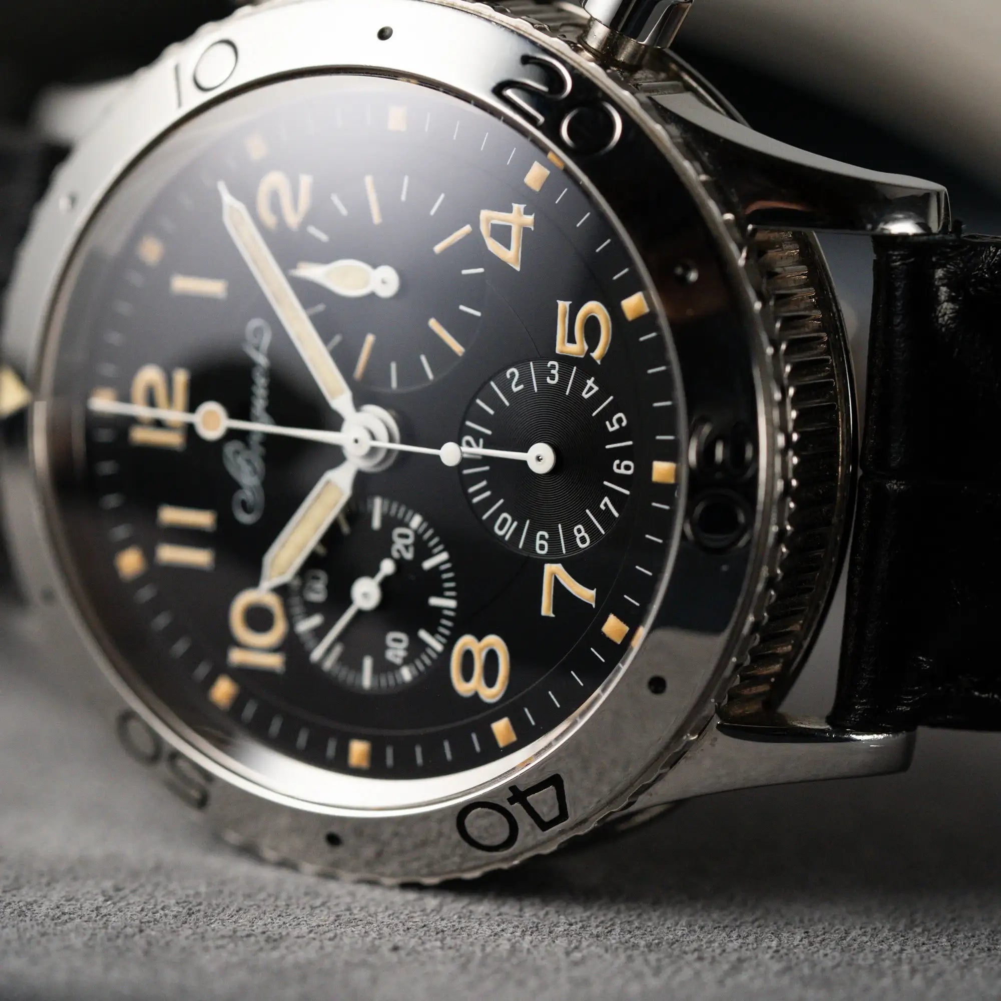 Detailaufnahme der seitlich liegenden Breguet Type XX Aéronavale mit der Referenz 3800ST und vergilbten Tritium-Zifferblatt am schwarzen Lederband