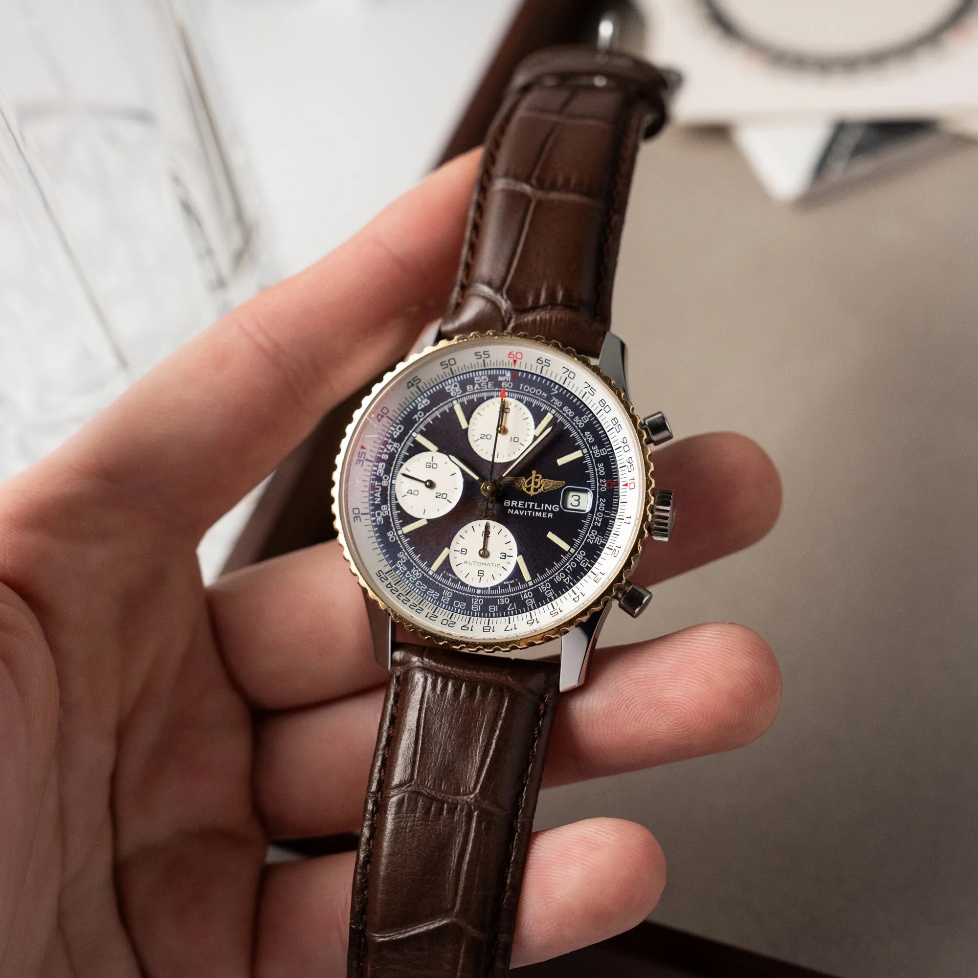 Mann hält den Breitling Old Navitimer mit Stahl-Gold-Gehäuse am braunen Lederband in seiner Hand