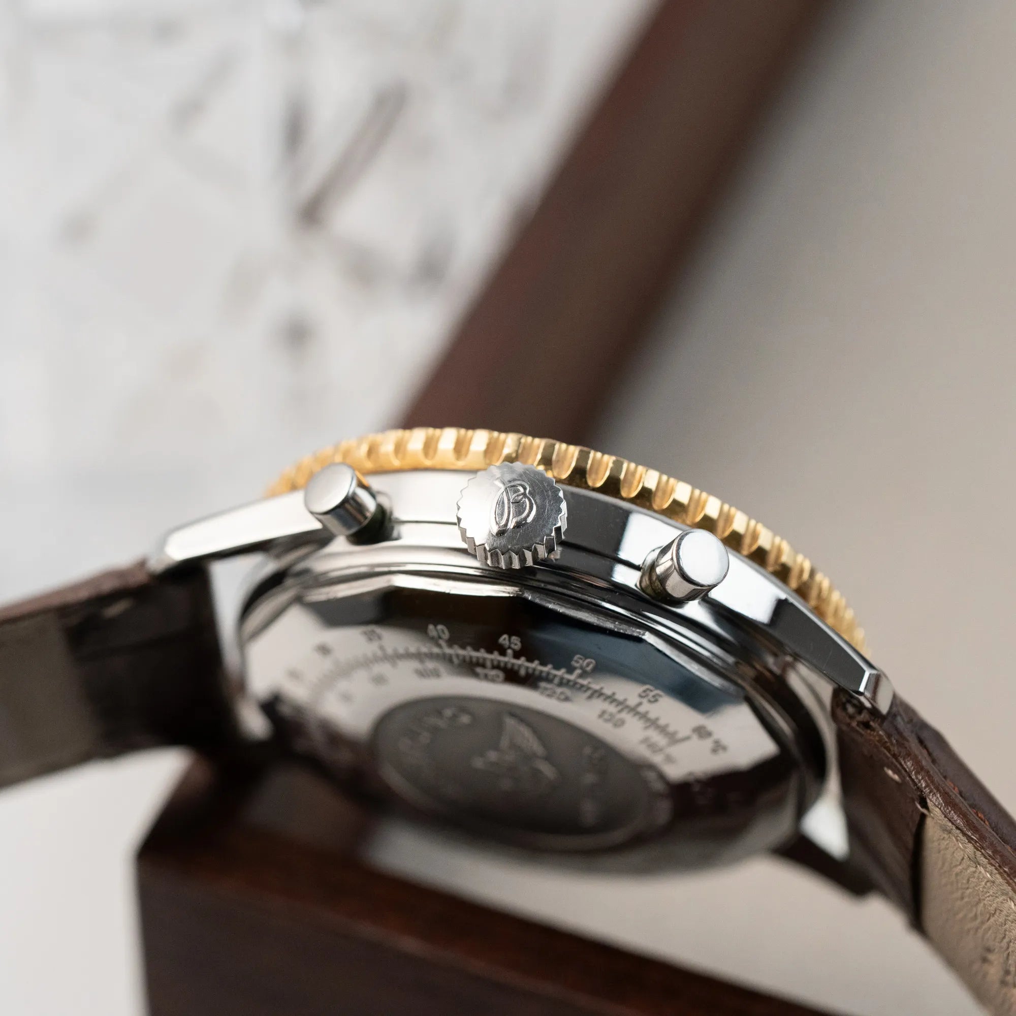Seitliches Gehäuse des Breitling Old Navitimers mit Stahl-Gold-Gehäuse am braunen Lederband mit Blick auf die Krone und die Chrono-Pusher