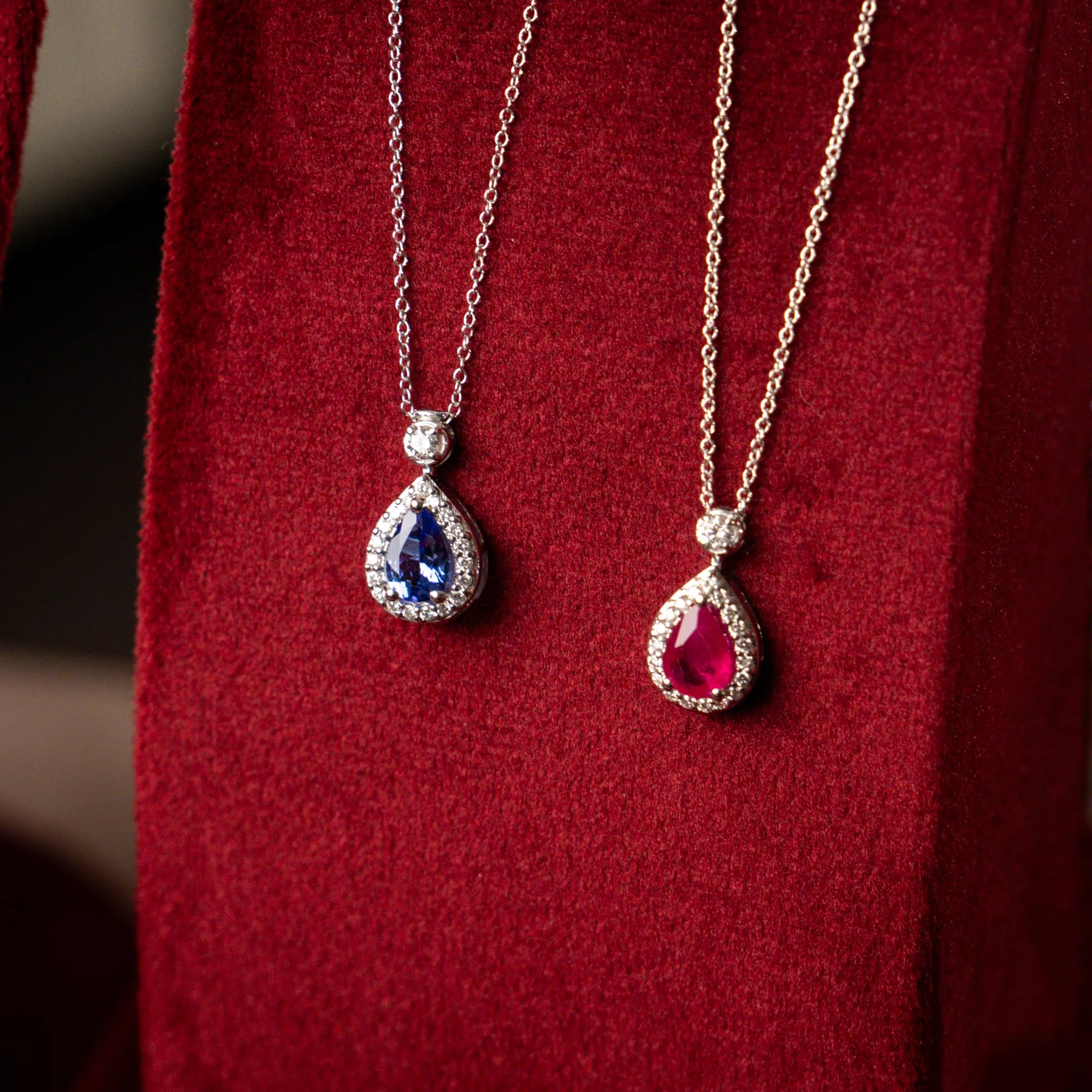 Fotografie der beiden Lunatica Roma Colliers CTND-166 und ORD-166 von Lunatica Roma mit jeweils einem Tansanit-Tropfen und Rubin-Tropfen als Anhänger, die mit Diamanten umrandet sind