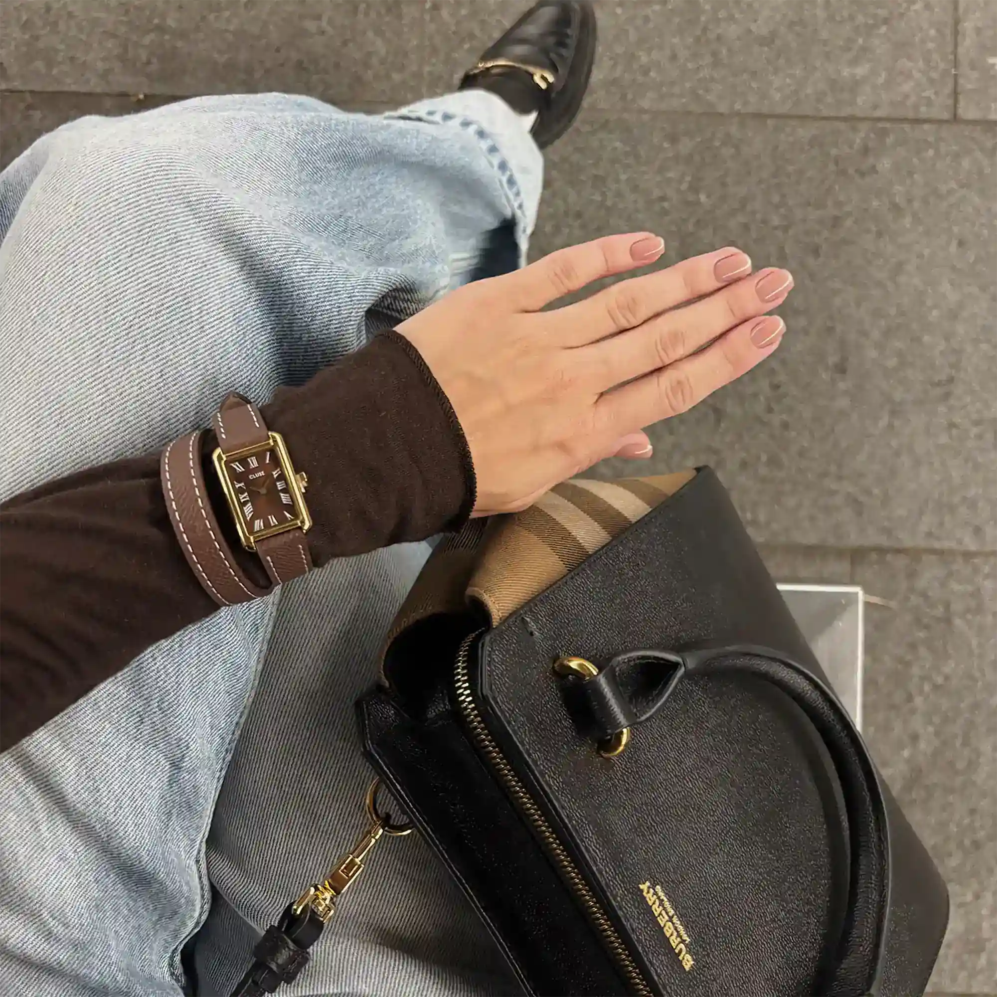 Lifestylebild mit der goldfarbenen Cluse Damenuhr Belisenna CW15006 mit braunem Zifferblatt mit römischen Indizes in einem eckigen Uhrengehäuse an einem braunem Doppel-Lederband