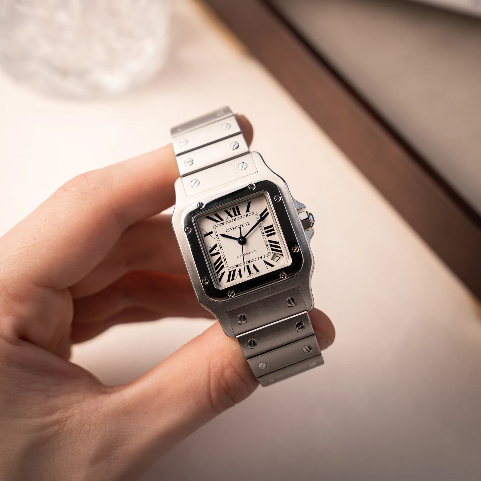 Mann hält die Cartier Santos Galbée 2823 Armbanduhr in Edelstahl mit weißem Zifferblatt in seiner Hand und präsentiert die Uhr in die Kamera