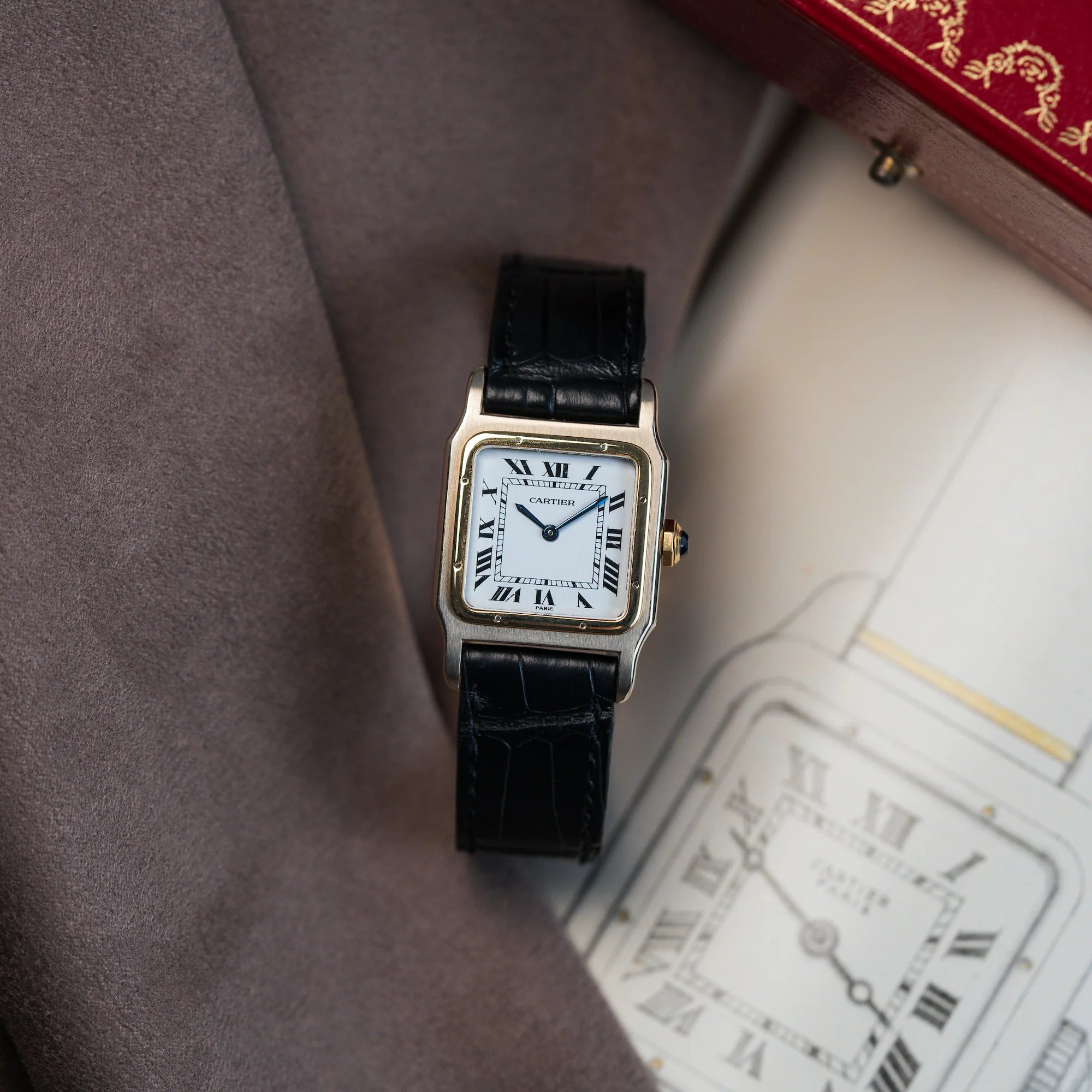 Produktfotografie der Cartier Santos Dumont "Deux Ors" mit weißem Paris Dial mit einer Zeichnung als Hintergrund