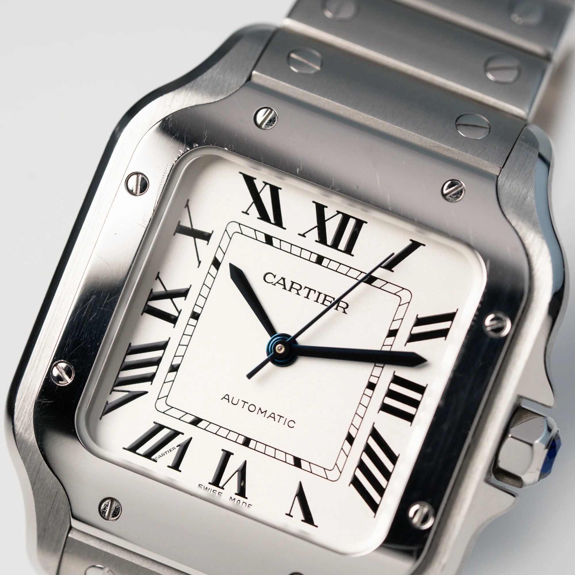 Detailaufnahme des Zifferblatts und der Lünette der Cartier Santos Medium mit dem klassischen weißen Zifferblatt mit römischen Indizes