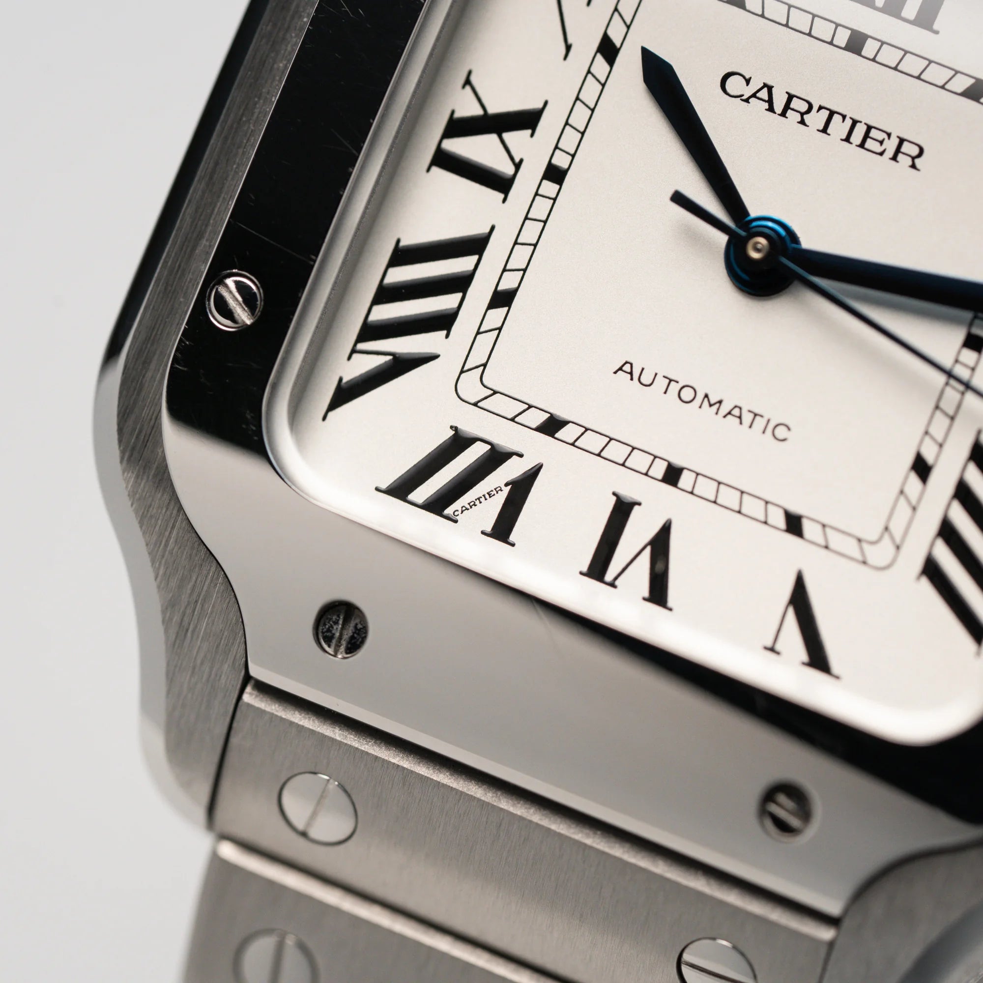 Makroaufnahme der Lünette und des weißen Zifferblatts mit römischen Indizes der Cartier Santos Medium
