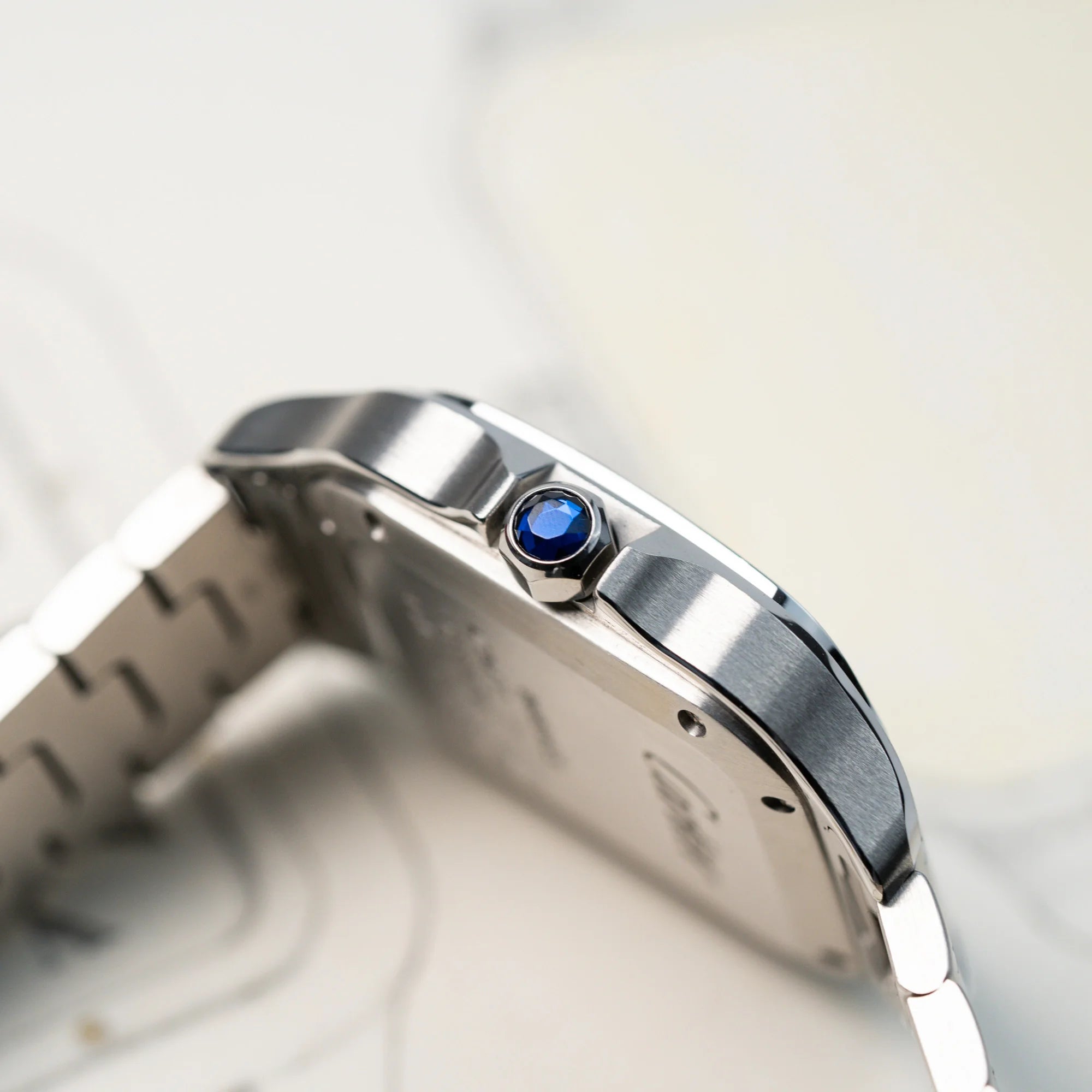 Detailaufnahme des seitlichen Gehäuse mit Saphir-Krone der Cartier Santos Medium mit dem klassischen weißen Zifferblatt mit römischen Indizes