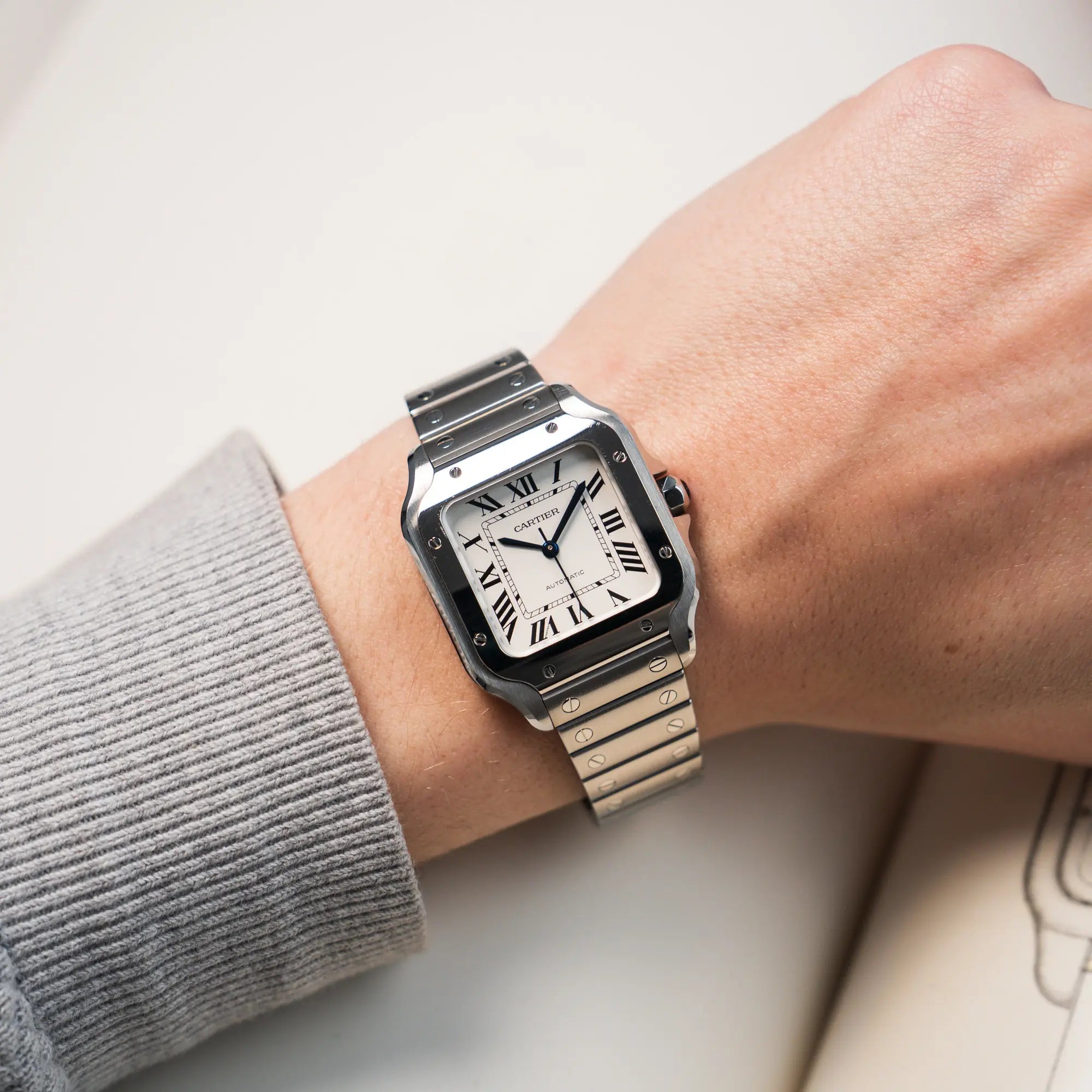 Mann trägt die Cartier Santos Medium mit dem klassischen weißen Zifferblatt mit römischen Indizes an seinem Handgelenk