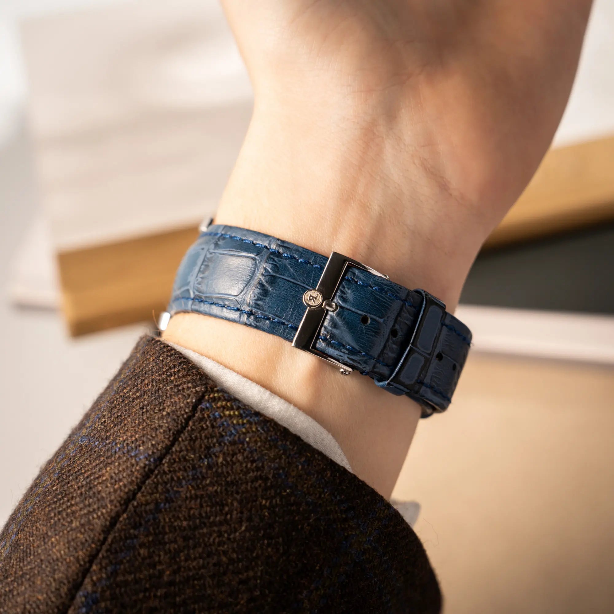 Mann trägt die Chronoswiss Imperia Constanze mit diamantbesetzten-Stahlgehäuse mit schwarzem Zifferblatt und präsentiert das petrol-blaue Lederband mit Stahl-Dornschliesse