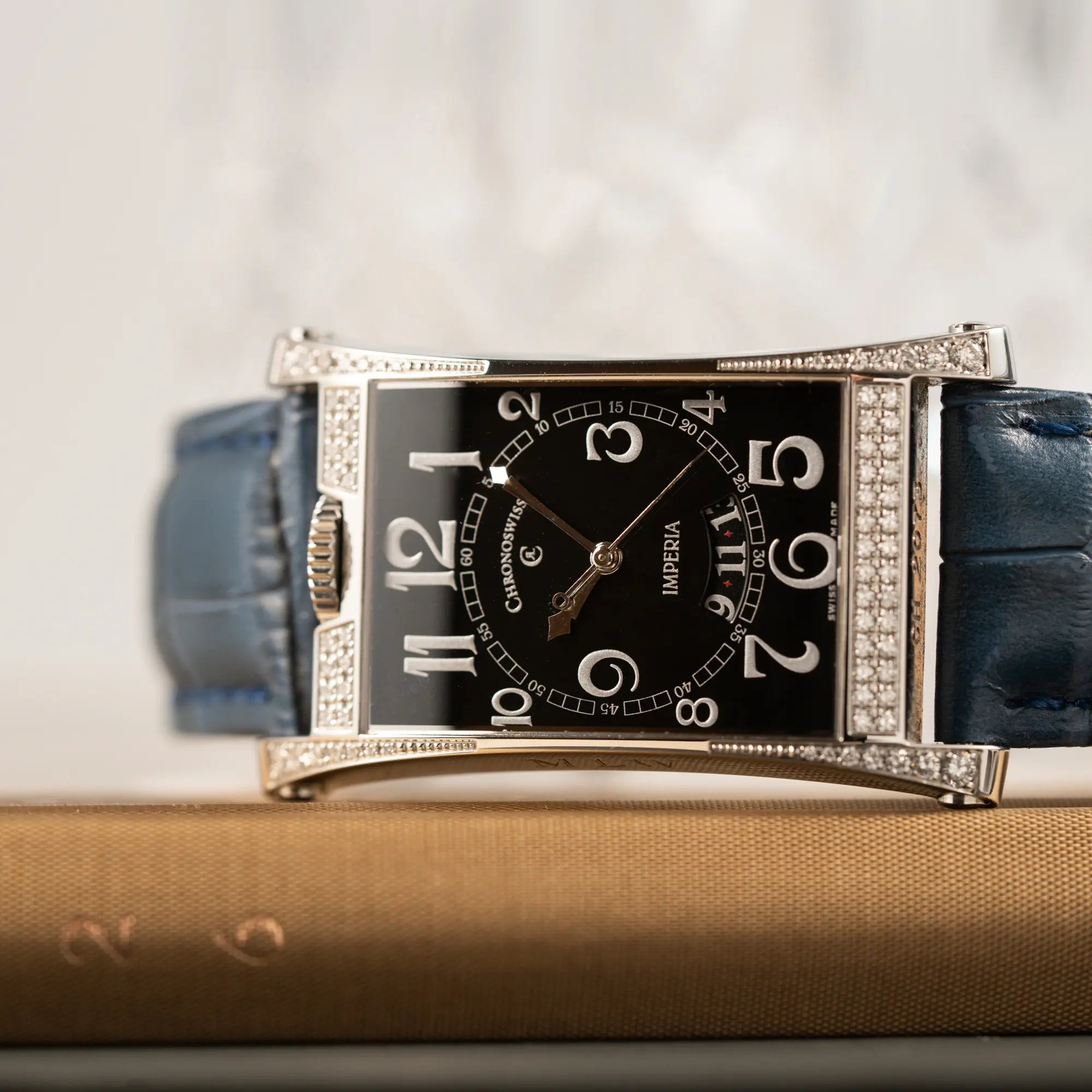 Detailaufnahme der Chronoswiss Imperia Constanze mit diamantbesetzten-Stahlgehäuse mit schwarzem Zifferblatt an einem petrol-blauem Lederband