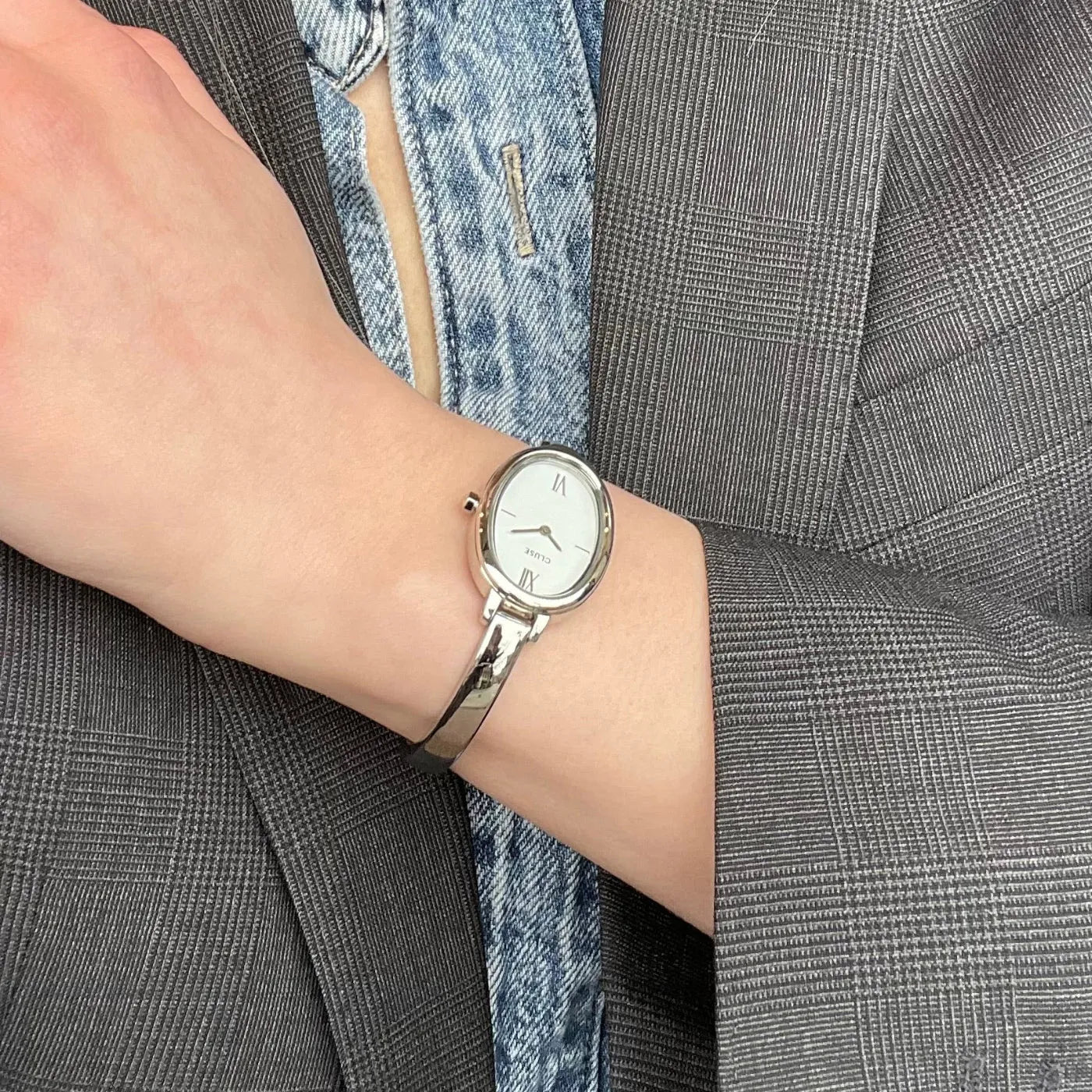 Frau trägt die silberfarbenen Cluse L'Ovale CW16102 Damenuhr mit weißem Zifferblatt an ihrem Handgelenk