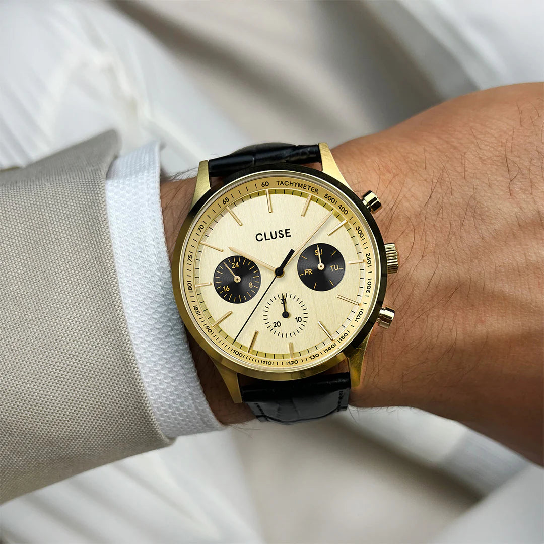 Wristshot an einem Männerhandgelenk des Chronographen für Herren CW21005 von Cluse mit goldfarbenem Gehäuse und schwarzem Lederband