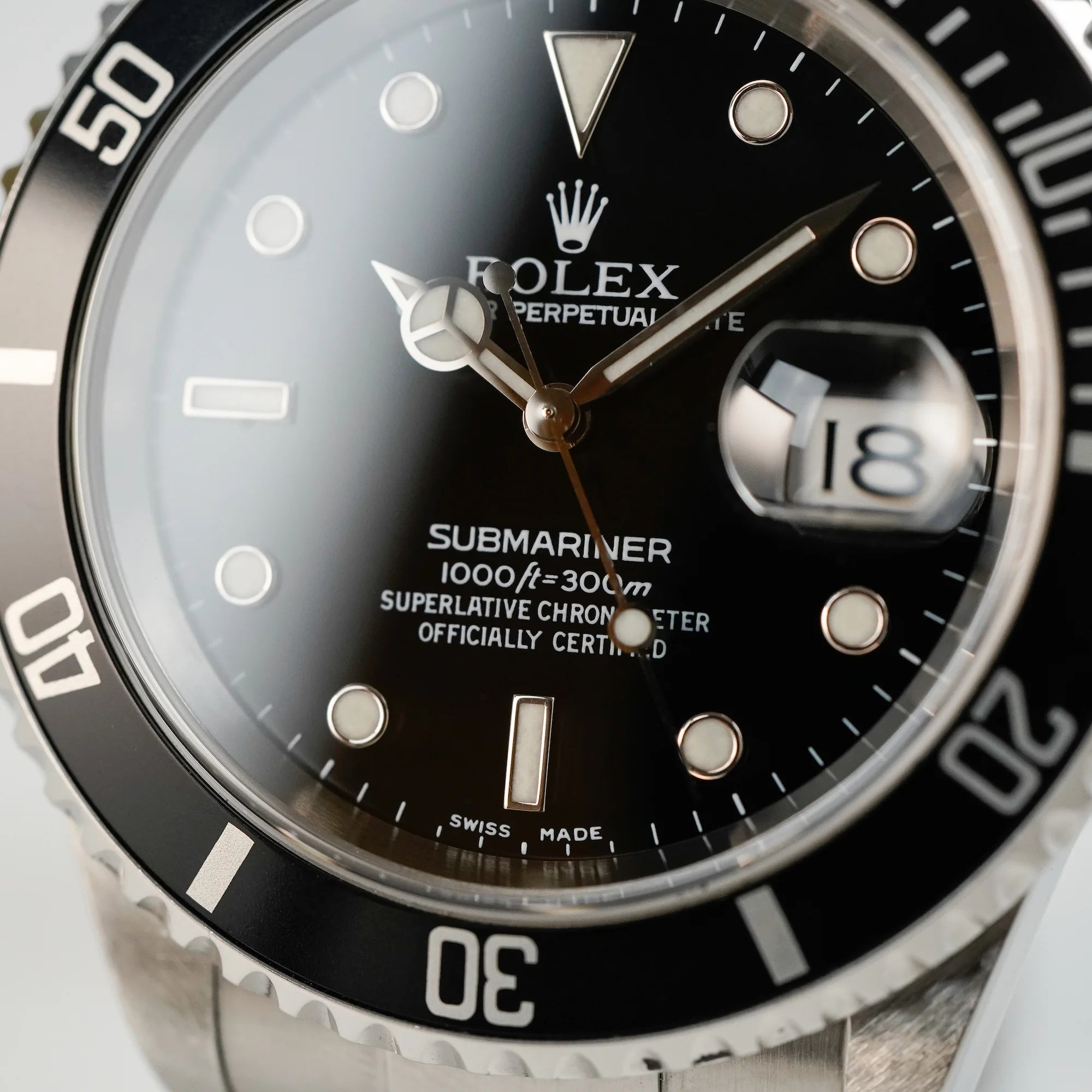 Makroaufnahme des Zifferblatts der Rolex Submariner Date in schwarz, Referenz 16610, mit Flat-Four-Lünette