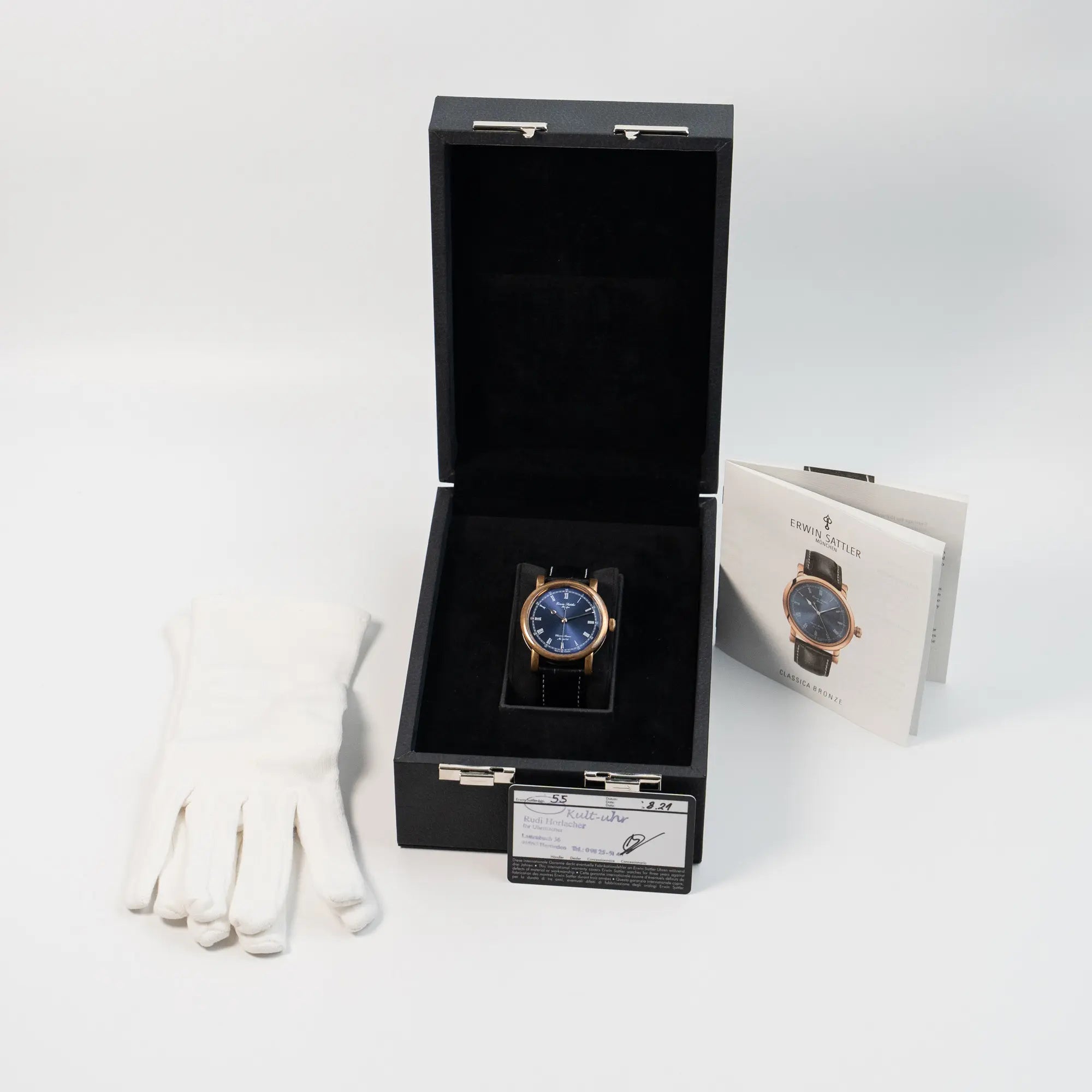 Erwin Sattler Classica Armbanduhr in einem Bronze-Gehäuse mit blauem Zifferblatt zusammen mit dem Lieferumfang, bestehend aus Uhr, Box, Garantiekarte, Booklets und Handschuhen