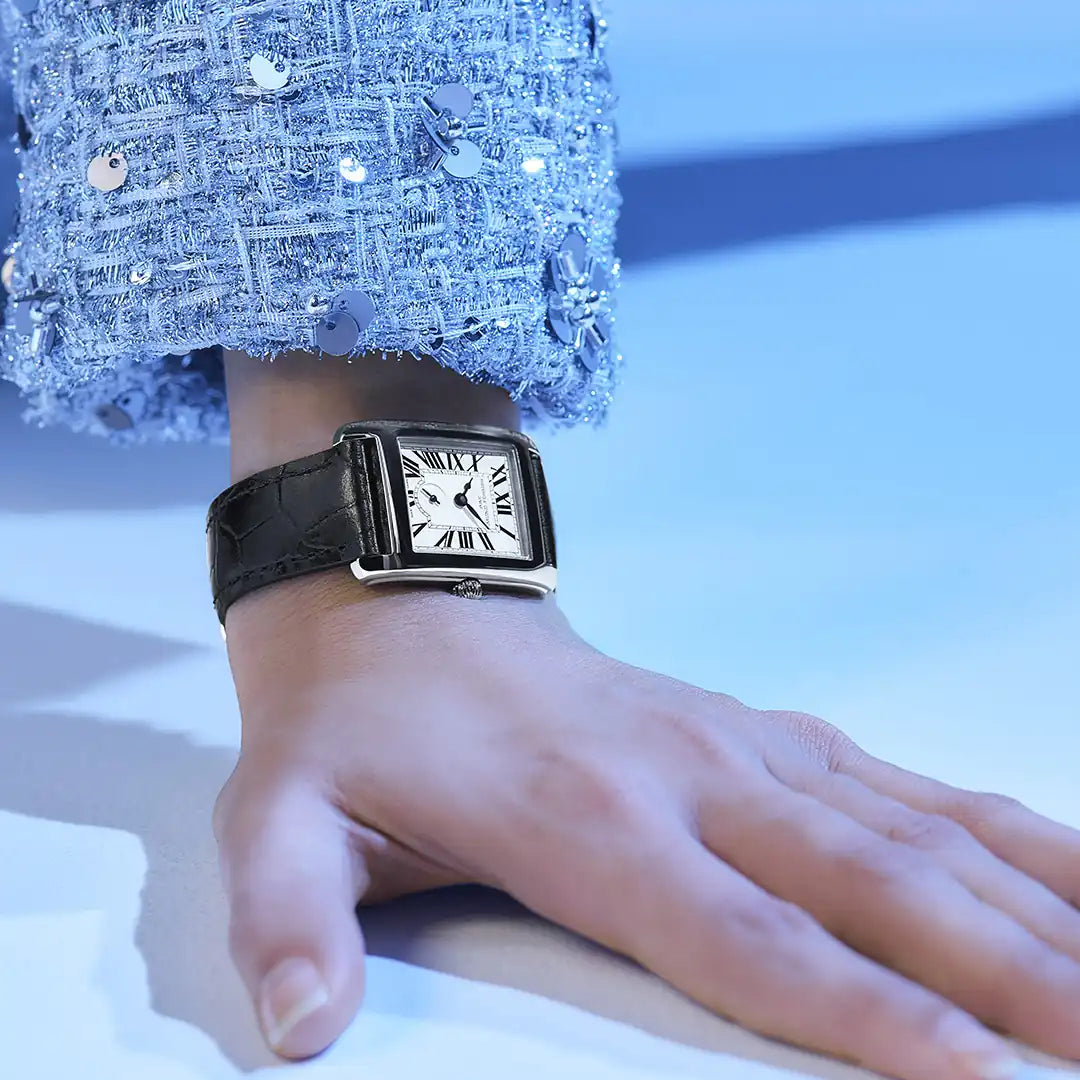 Frau trägt die Frederique Constant Damenuhr FC-235S2C6 aus der Classic-Kollektion mit einem rechteckigen Uhrengehäuse und einem silbernen Zifferblatt mit römischen Ziffern und der kleinen Sekunde auf 6 Uhr an ihrem Handgelenk